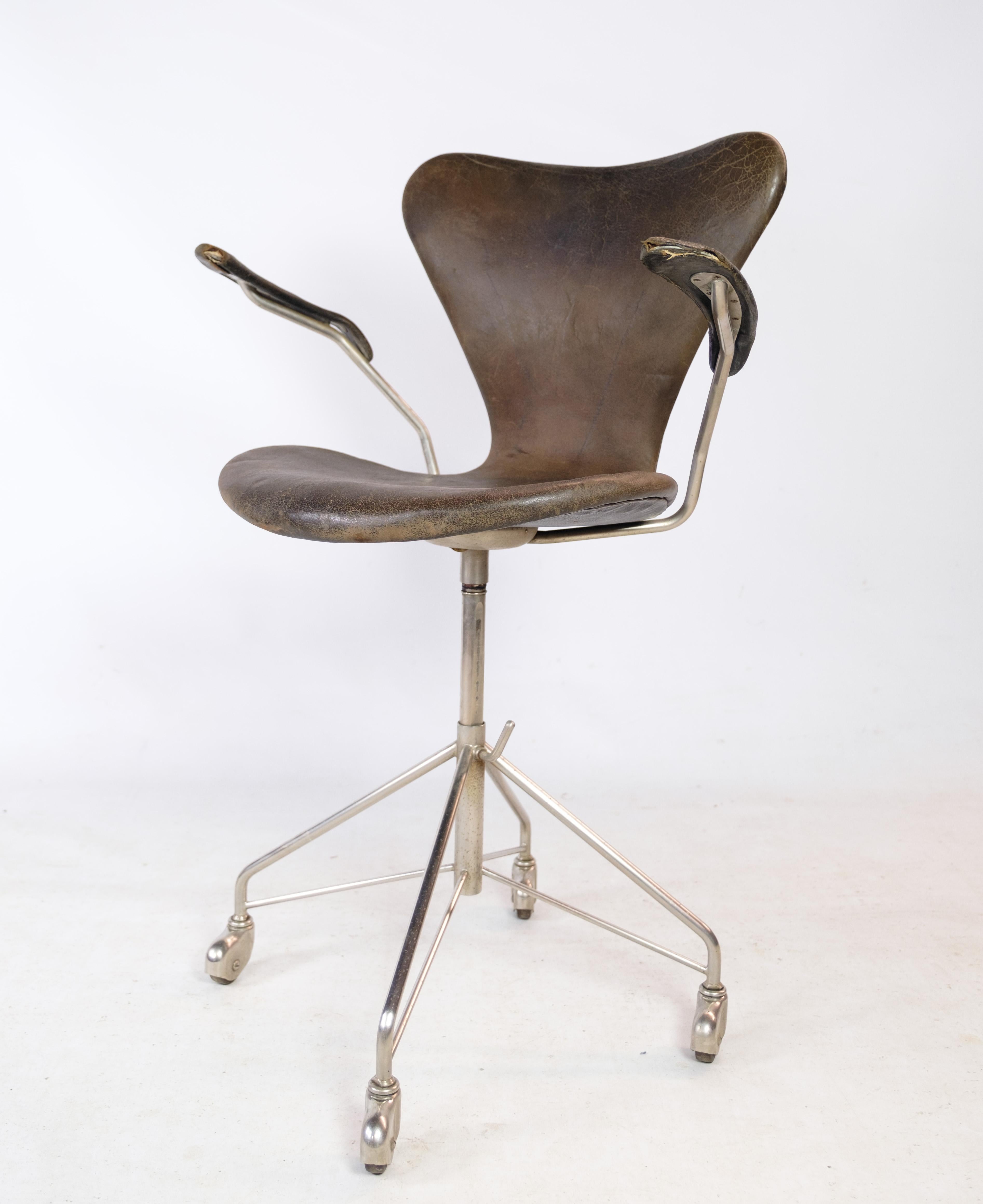 Seven office chair, model 3217, with armrests and swivel function in original dark brown leather designed by Arne Jacobsen in the 1950s and manufactured by Fritz Hansen. The chair is in used condition with patina and wear. Comes with original