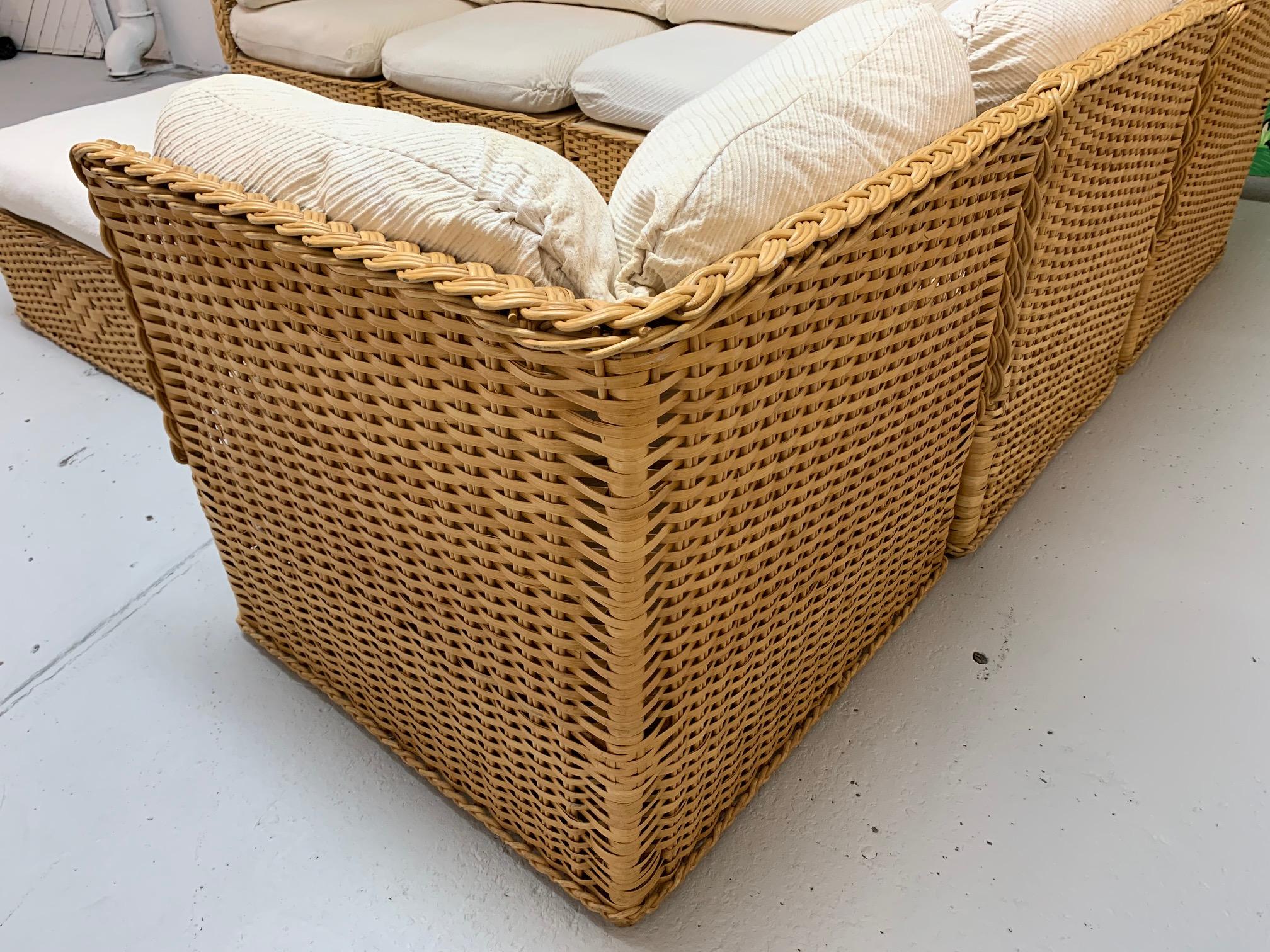 Large 7-piece wicker sectional sofa in the style of Michael Taylor features modular design and matching ottoman. Cushions in excellent condition with cream upholstered removable covers. Slight staining on some covers. Frames in very good condition