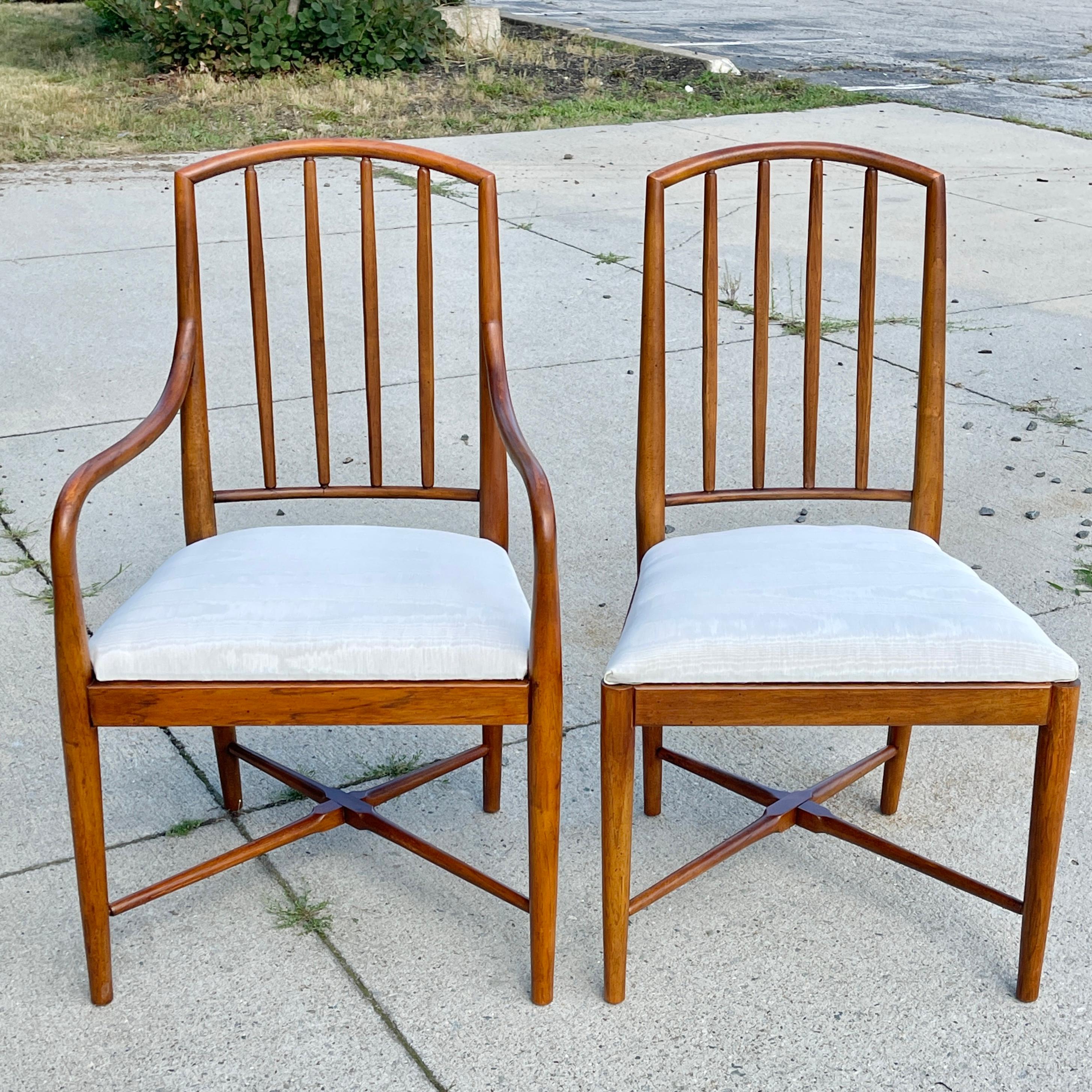 Seven sinewy curved walnut spindle-back dining chairs; 2 arm chairs and 5 side chairs, exceptionally well made (note cross-stretchers and tightness of joints, curved swan-like arms, hex blocks and bowed spindle rails). 
Maker unknown but clearly in