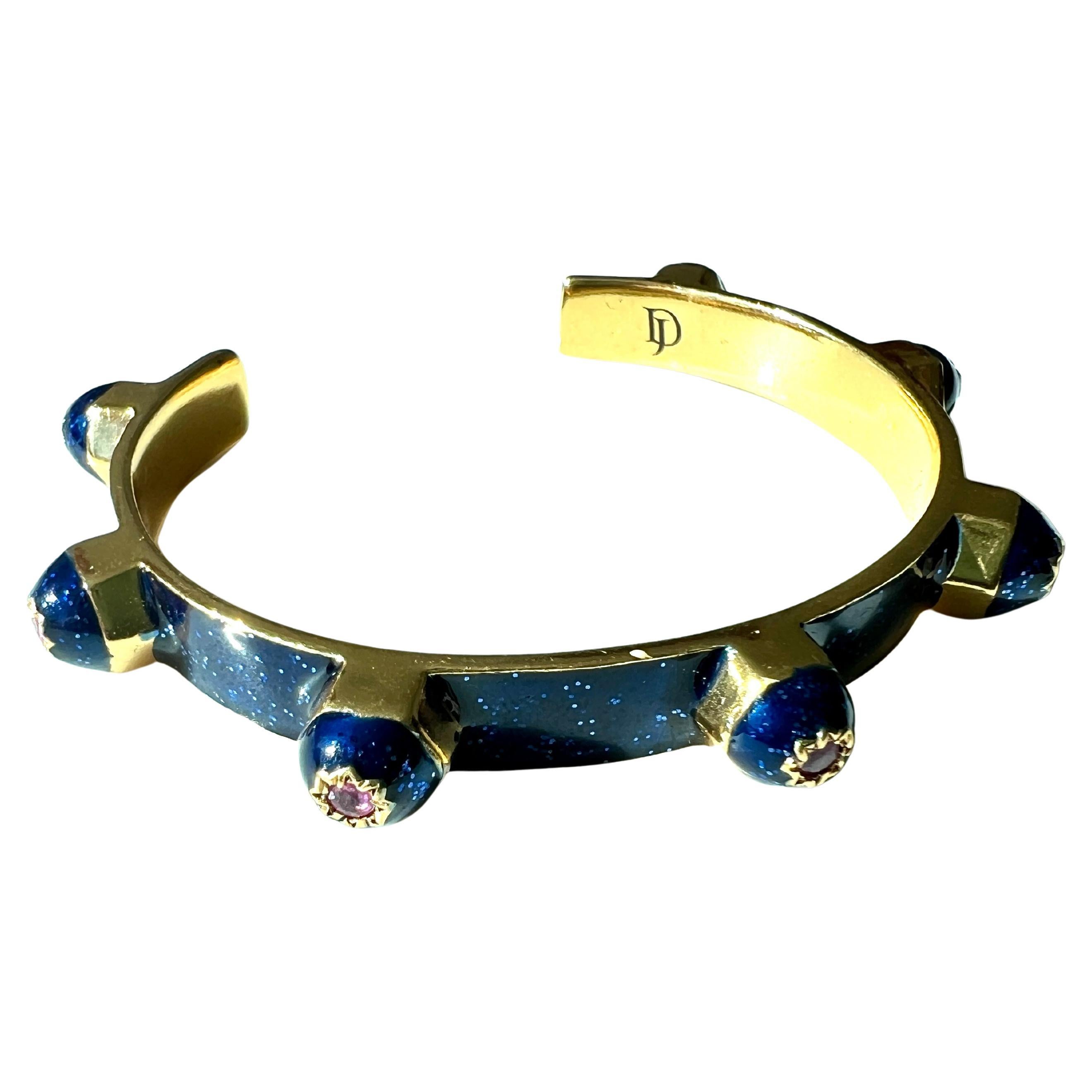Ce bracelet manchette en émail bleu de J DAUPHIN comporte sept rubis naturels sertis dans des étoiles gravées à huit branches, conçues en laiton plaqué or 14k. La forme large et sculpturale de la manchette ouverte allie l'inspiration victorienne à