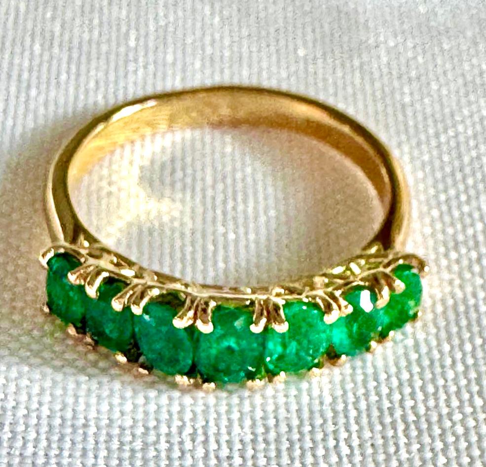 

Estate seven stone Colombian emerald ring. The graduated half-hoop ring of oval cut Fine AAA Colombian emeralds has excellent color, and clarity, mounted in 18K yellow gold.  Lovely to wear stacked with a gold band or other gemstone rings. 
The