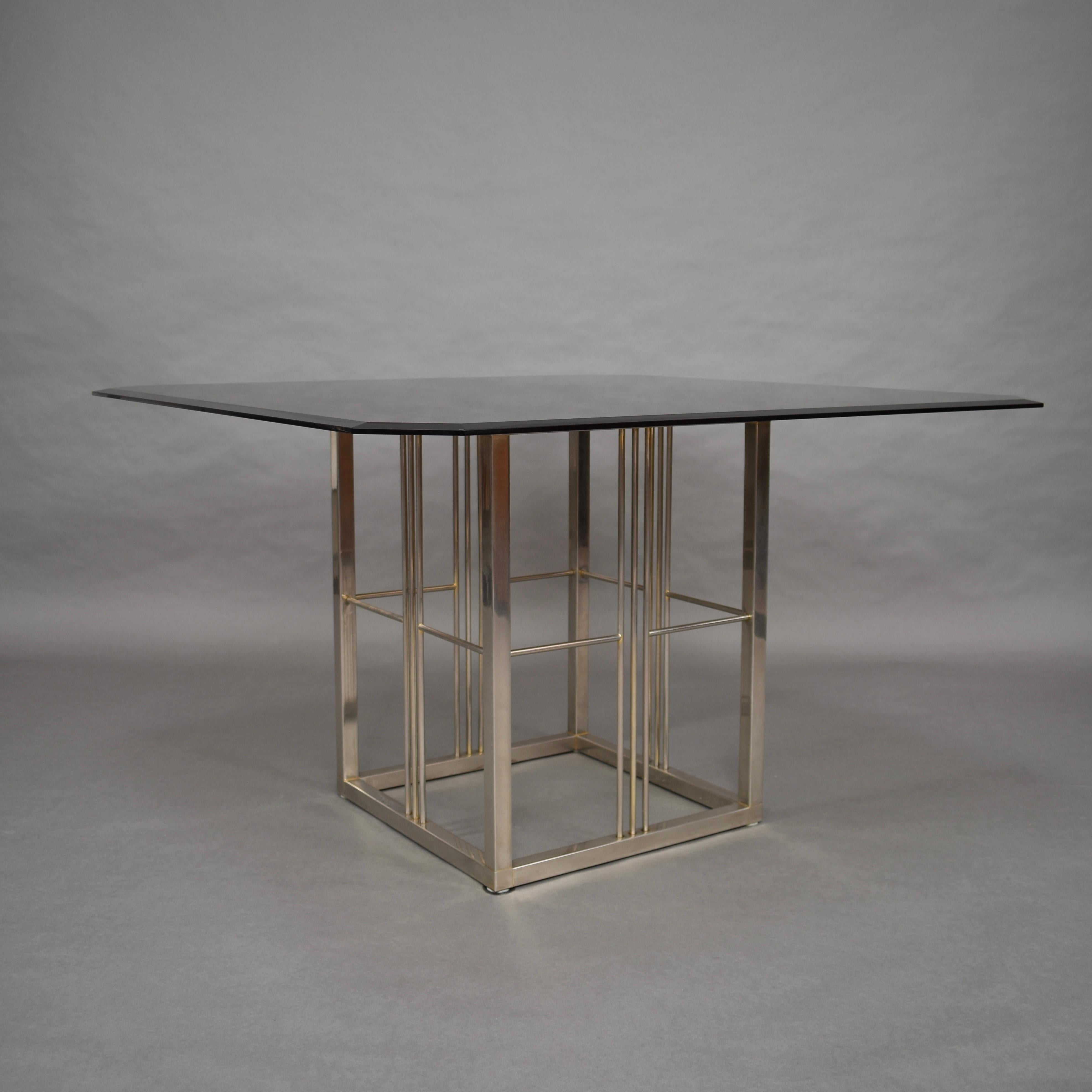 Seventies dining table in the style of Pierre Cardin. Originally the base was covered in gold leaf but that has almost all faded away. The top is made of brown smoked glass of heavy quality with cut corners.
The table is probably of Italian,