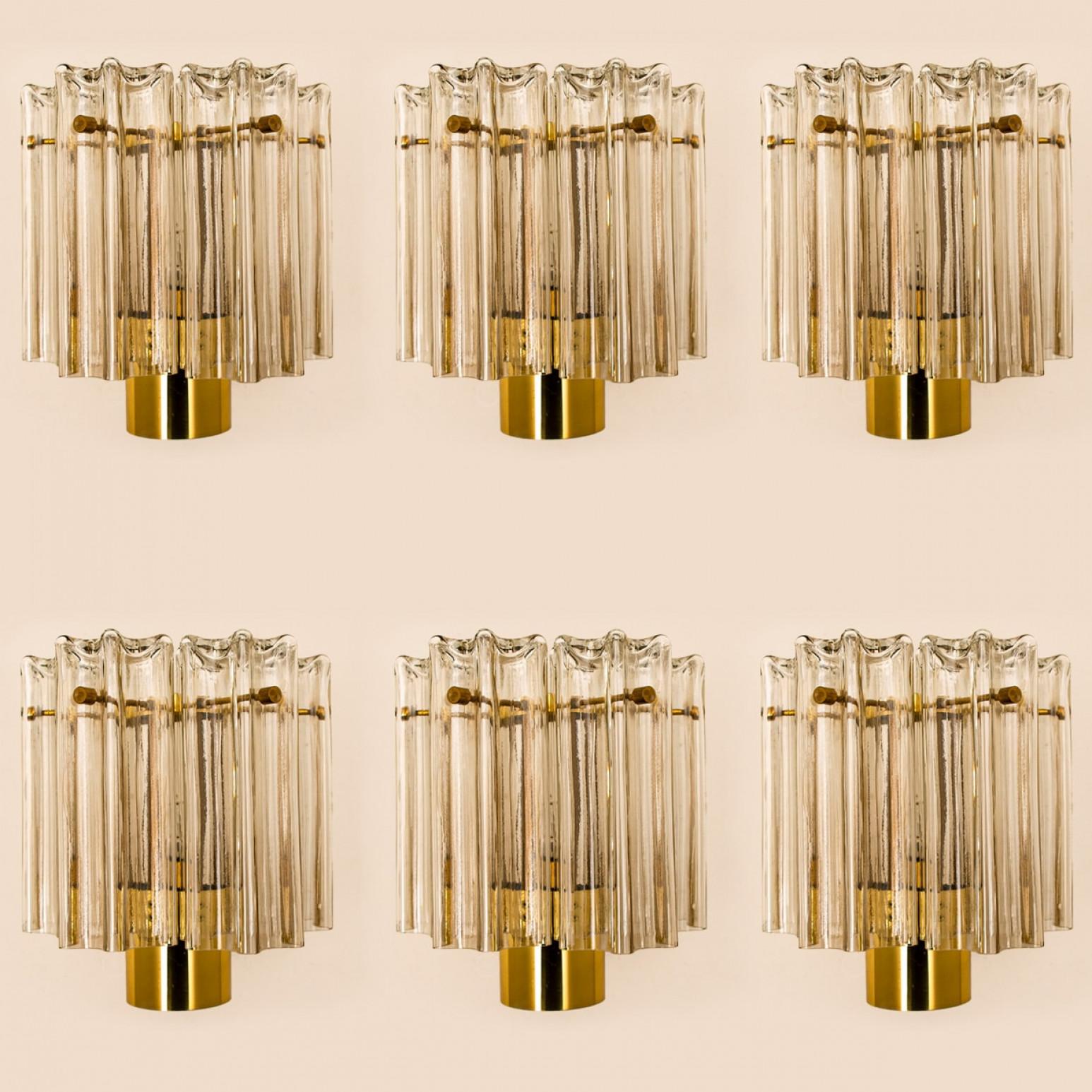 Several beautiful Murano glass wall lights, designed in Germany around the 1960s. These messing wall lights are handcrafted and of high quality.

Murano tubes in clear glass hanging on a brass plate. Illuminates beautifully. The timeless elegance of