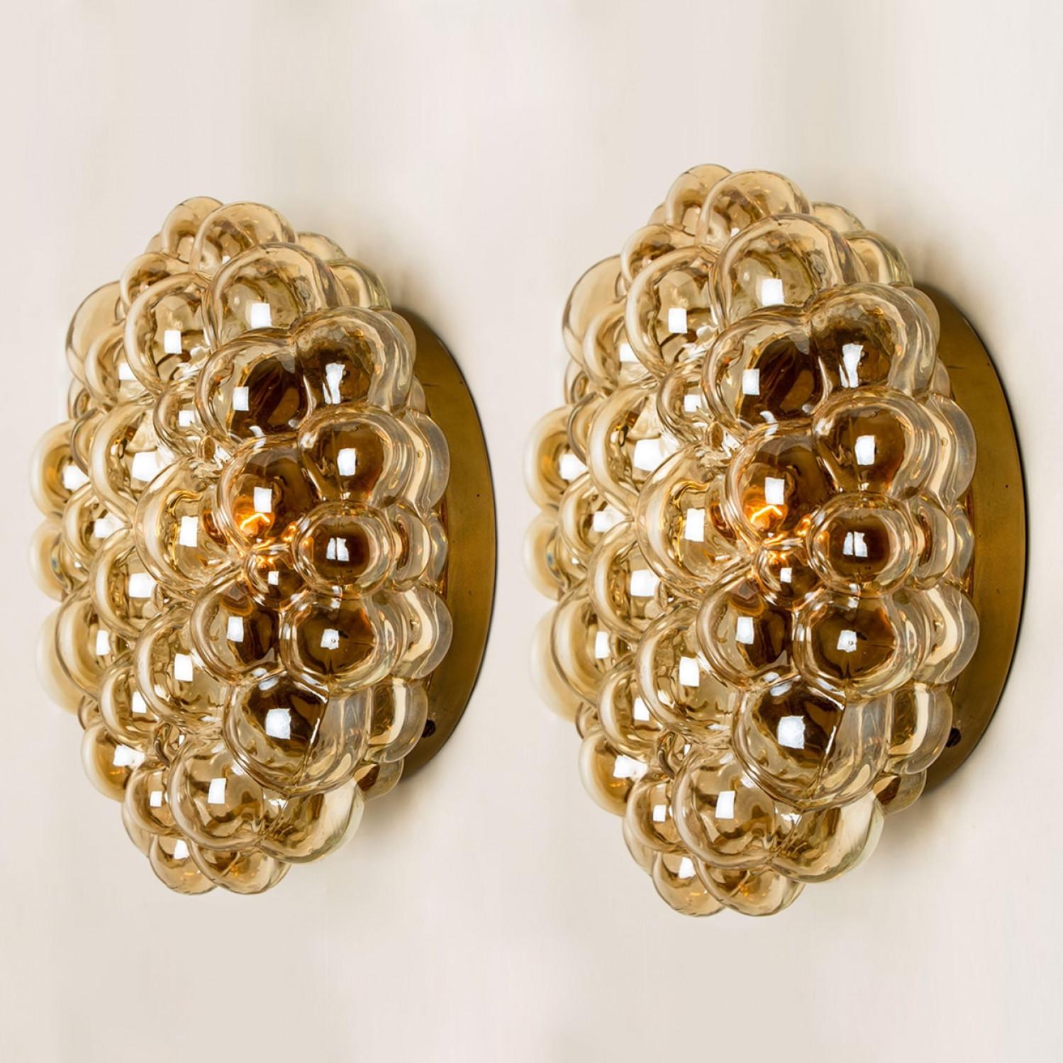 Beautiful clear bubble glass wall light designed by Helena Tynell around 1960-1970 in Europe, Germany. The bubbled glass gives a wonderful glow. The glass is mounted on a gold colored metal back plate. There are multiple similarly designed lights