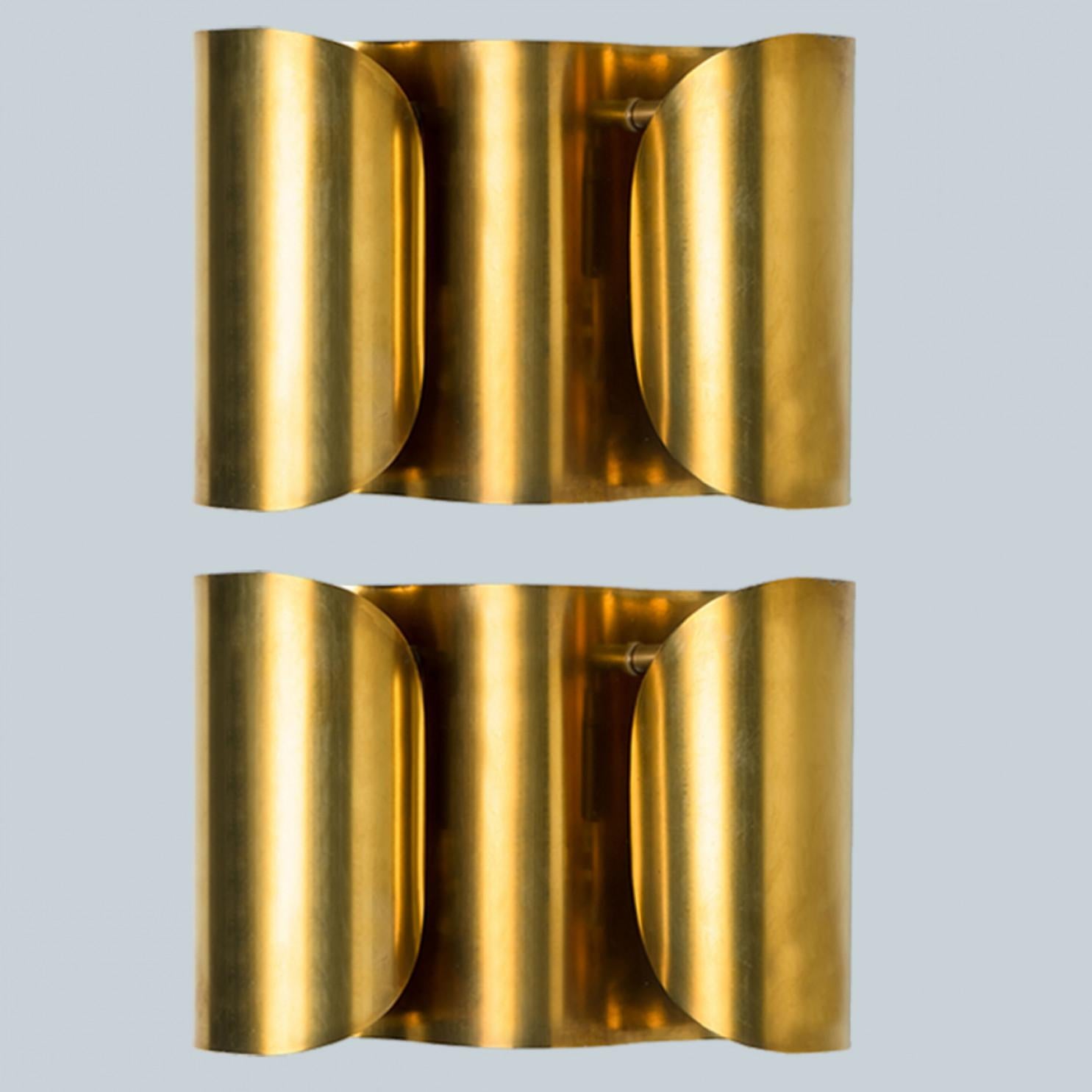 Beautiful  brass wall lights. Original and well kept. Each wall light  composed of a large sheet of brass curled towards the middle, with a bulb in the middle.

The wall lamp suits many environments, from mid century to Hollywood Regency, from