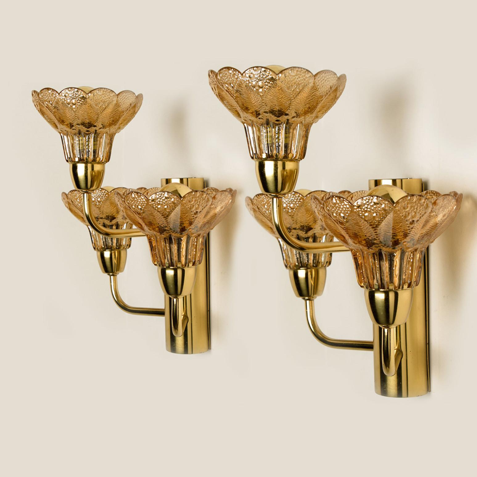 This flower like wall sconce is made of brass with glass flowers and are from Germany. The sconce shows three amber glass flowers, each contains one light bulb.

Each glass flower shade has textured petals and is securely screwed in place. Each