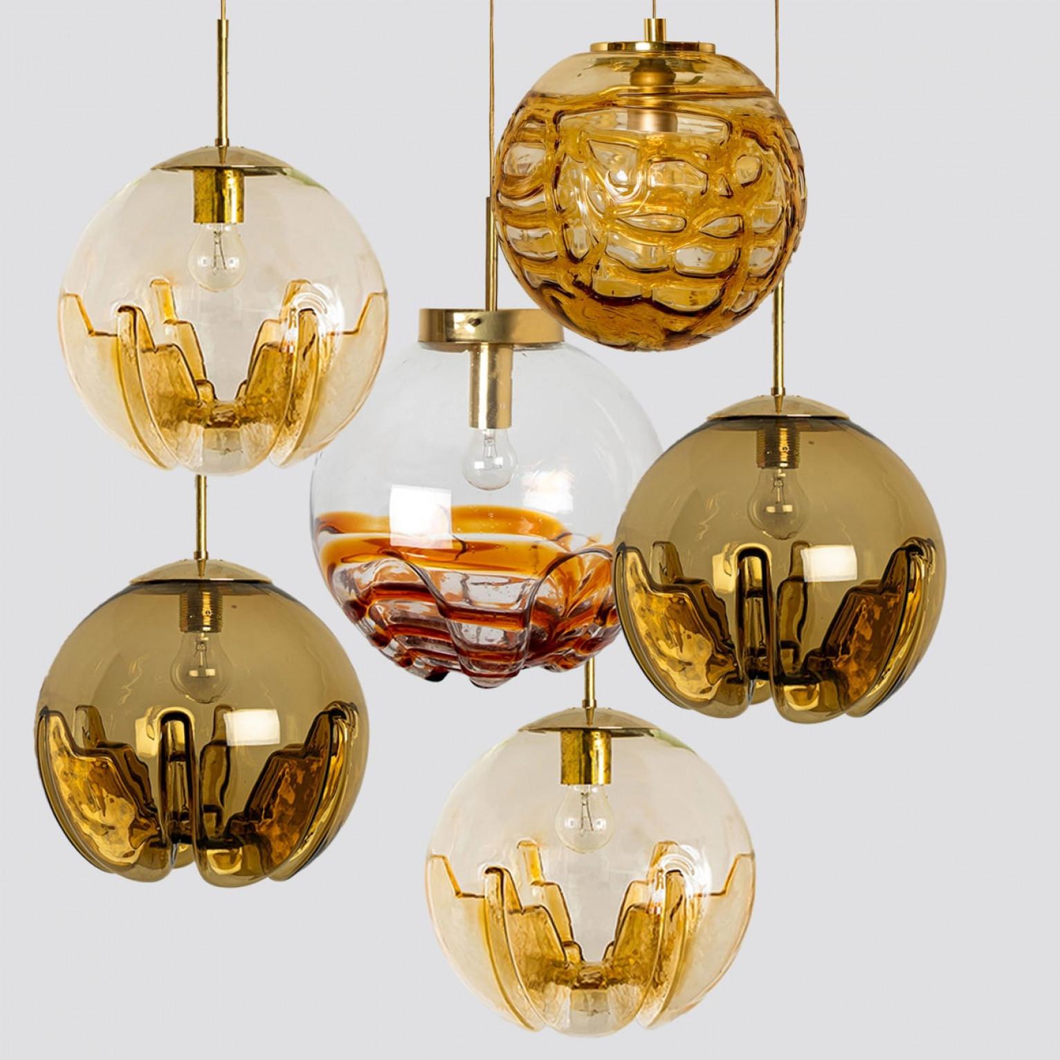 A collection of beautiful and stylish glass pendant lights made in Germany and Italy around the 1960's. The Doria light is made of yellow clear glass in a bubble shape. The Kaiser light is made of clear red-brown glass and the Mazzega light is