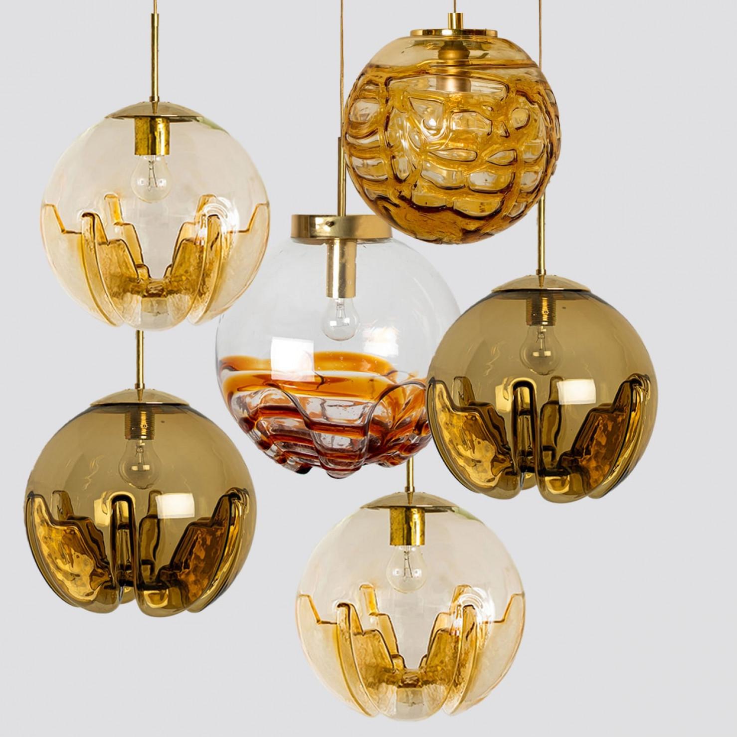 Una collezione di bellissime ed eleganti lampade a sospensione in vetro realizzate in Germania e in Italia intorno agli anni '60. La lampada Doria è realizzata in vetro giallo chiaro a forma di bolla. La lampada Kaiser è realizzata in vetro chiaro