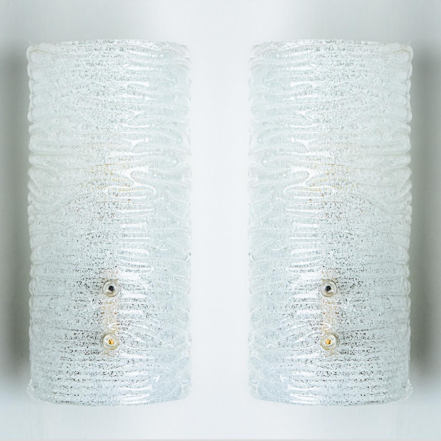 Beautiful high quality light fixture made by Kalmar, Austria. Manufactured in mid century, circa 1970 (at the end of 1960s and beginning of 1970s).

This wall light features lights made of handmade ribbled ice glass and brass back plate. The sides