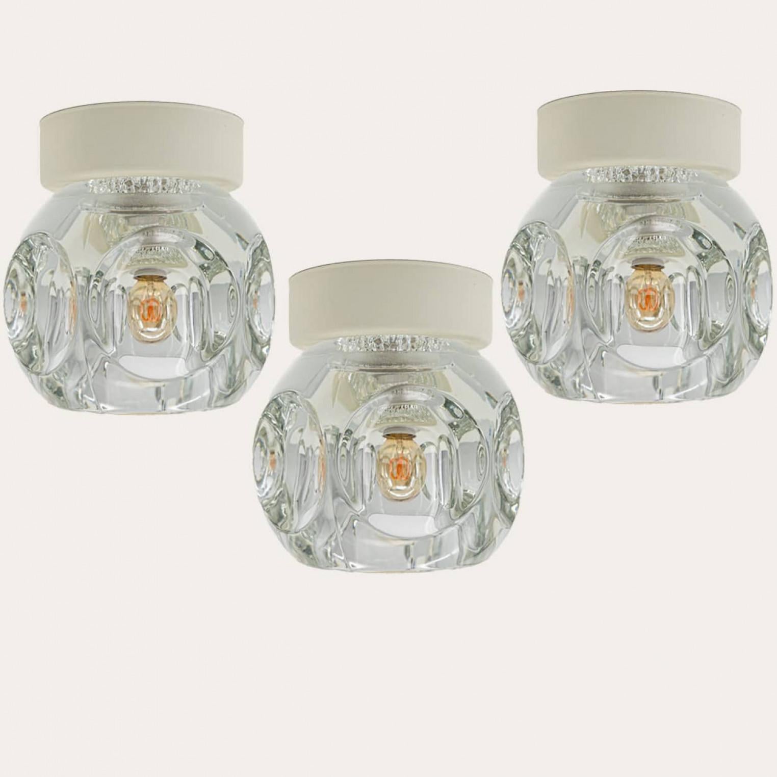 Ice Cube lamps impresses with wonderfully shiny glass and unique design from 1972. With warm off white back plate. Can used as wall or flush light.

The light cubes were manufactured by the renowned lamp manufacturer Peill and Putzler in Germany and