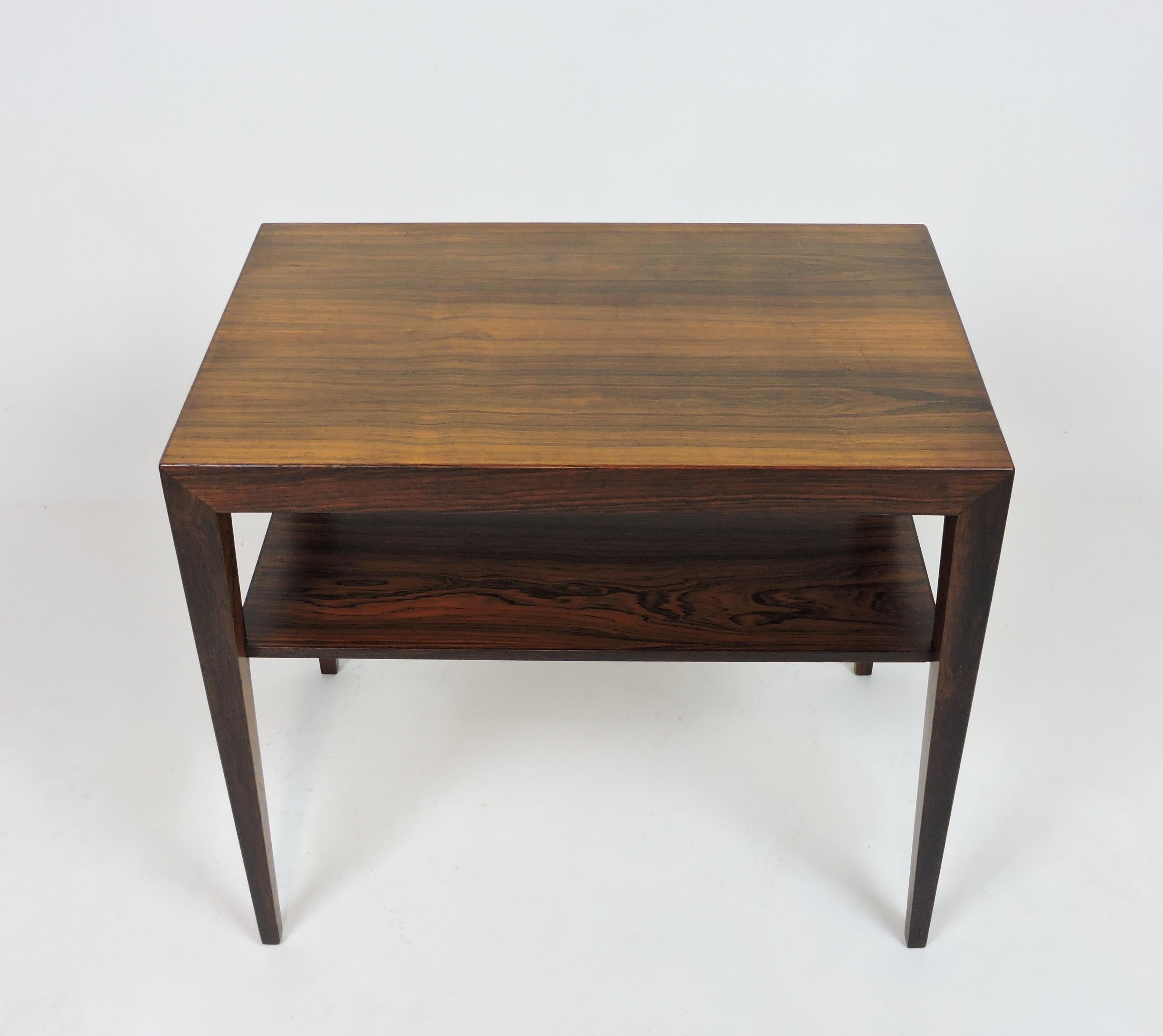 Elegant end or side table in rosewood designed by Severin Hansen and made in Denmark by Haslev Mobelsnedkeri. This well crafted table has a nicely proportioned minimalist design with tapered legs and includes a shelf. Marked with both Haslev