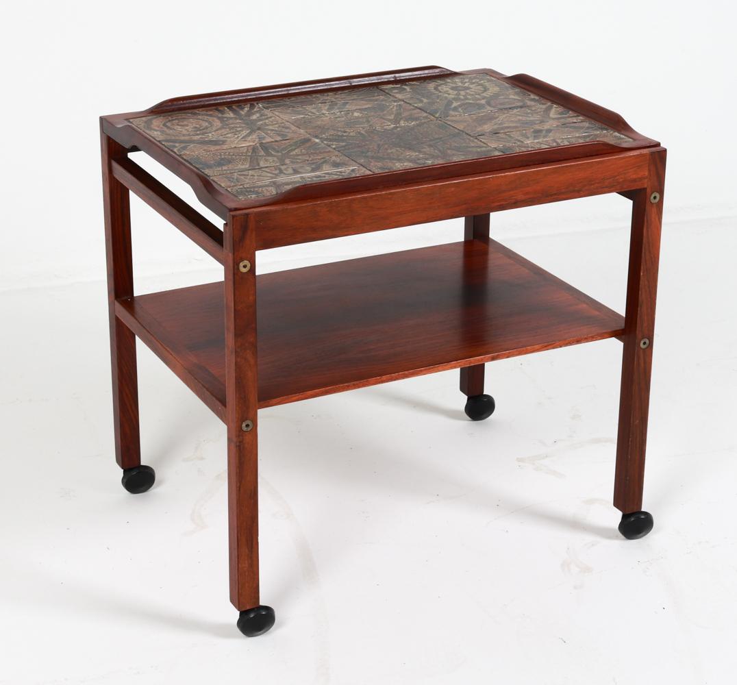 This quaint little serving cart was made in Denmark, designed by Severin Hansen for Haslev Mobelfabrik. It was made in the 1960's, which is evident from its style and design. Crafted from rosewood, this serving cart strikes a stunning and elegant