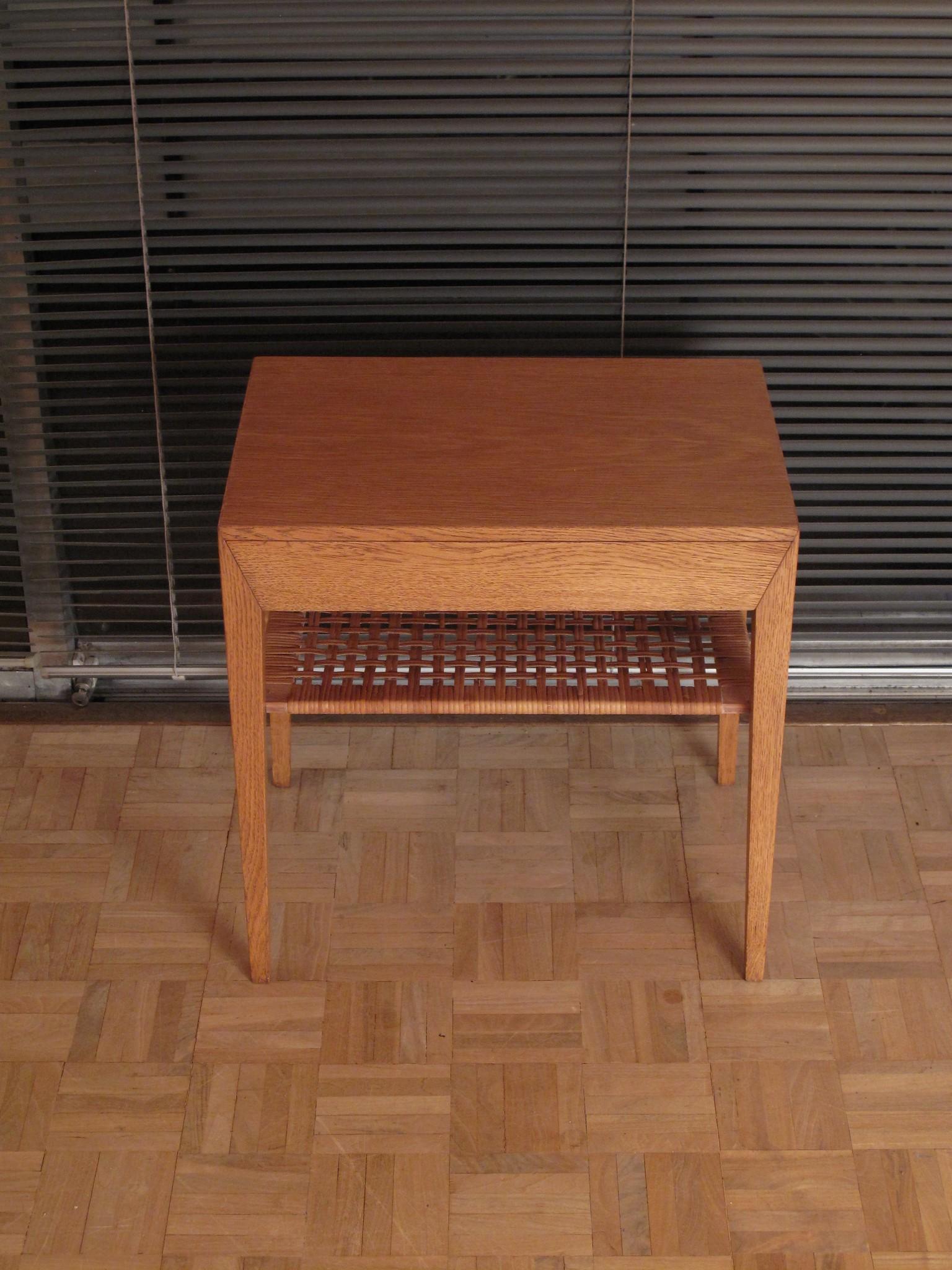 Very desirable bedside table or side table designed by Severin Hansen for Haslev møbelsnedkeri

Finished in oak with a rattan woven shelf beneath a single drawer. Offered in very nice condition. There are some minor losses to the rattan however it