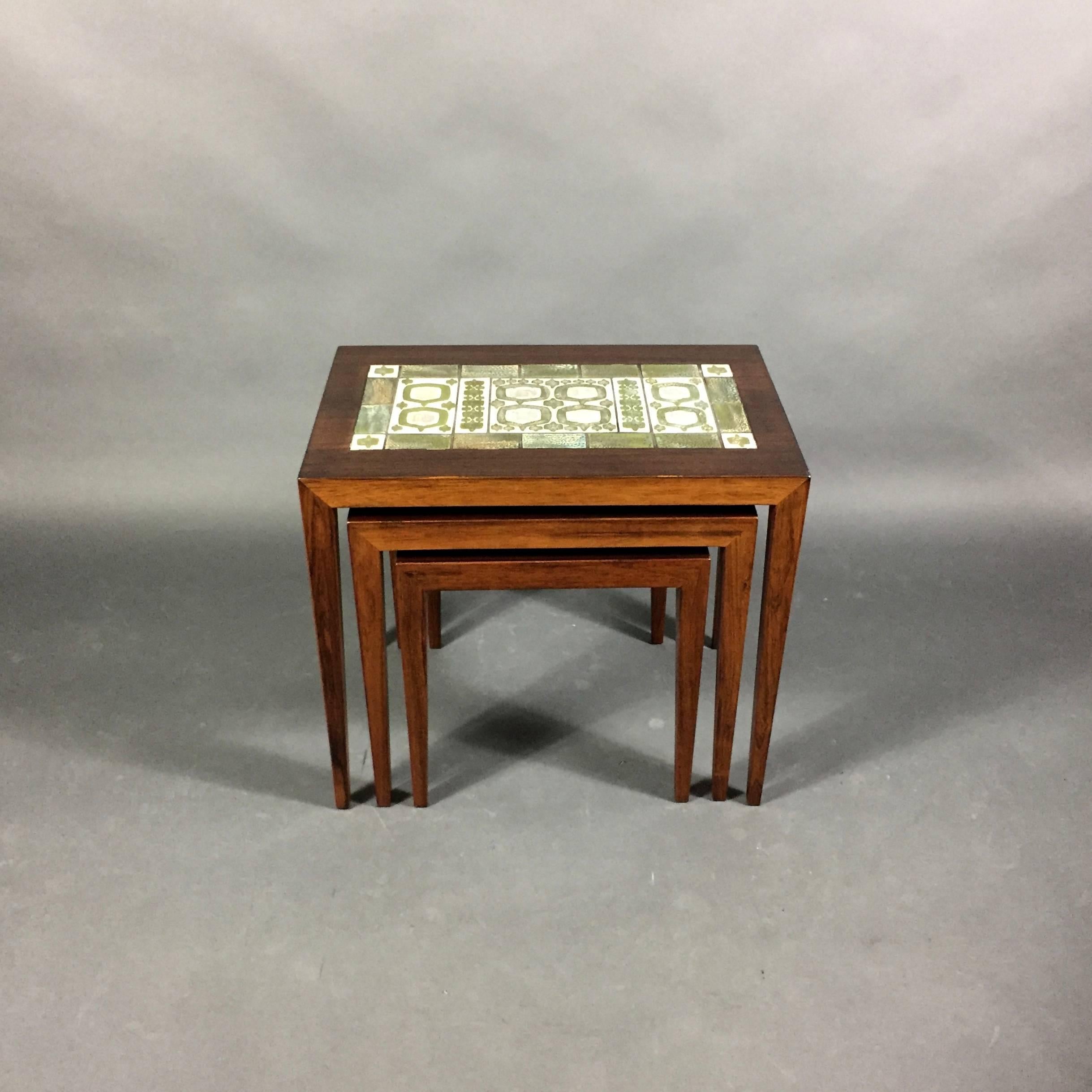 Beautifully crafted set of three nesting tables in Brazilian rosewood with simple and sleek legs designed by Severin Hansen in 1960s and produced by Haslev Møbelsnedkeri in Denmark. This version includes a set of original tiles on the largest table