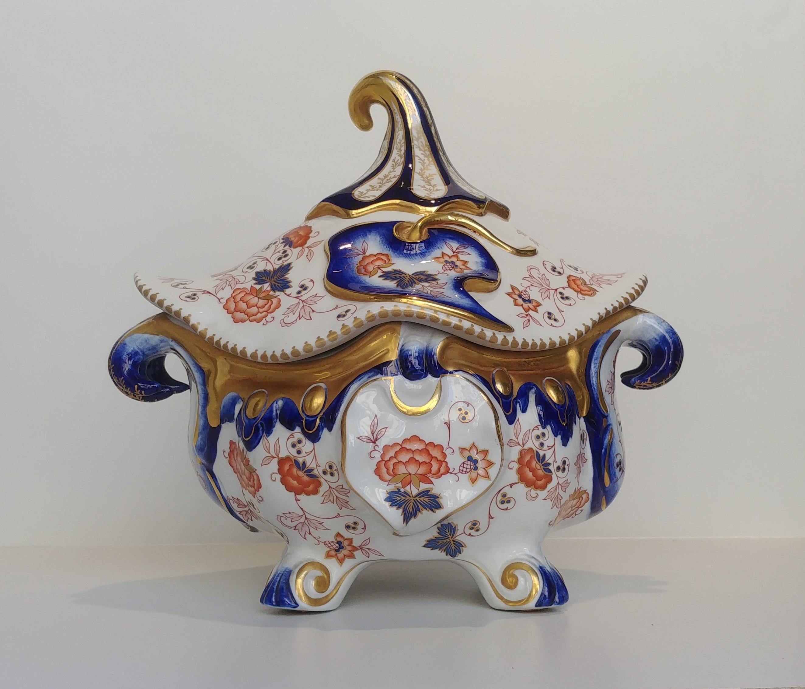 This porcelain tureen or centerpiece is finely hand painted with floral motifs made in Sevres in France in the 1970s. 
The object stands for its particular shape inspired by the Asian culture of pure gold in chromatic contrast with an intense