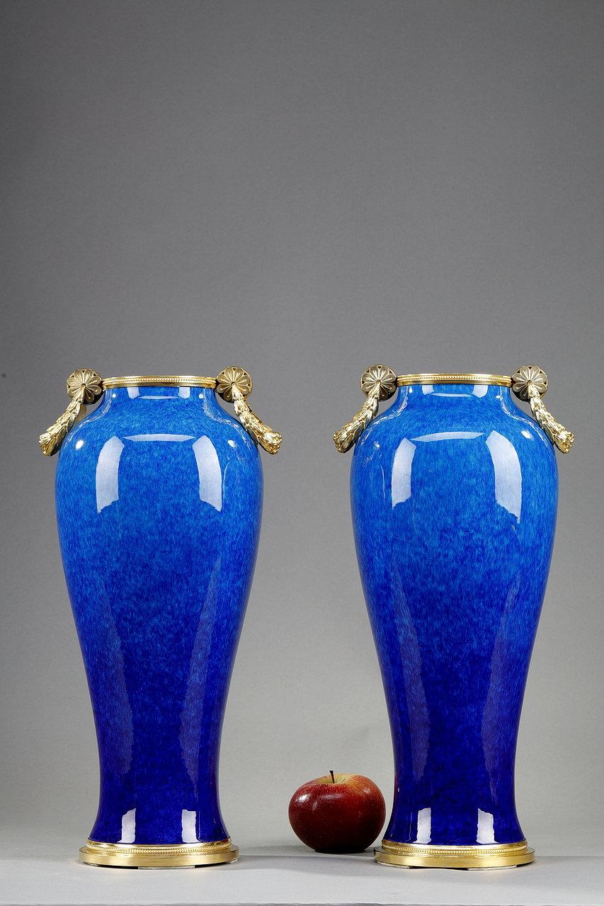 Paire de vases amphores en céramique de Sèvres, à décor marbré en camaïeu bleu. Chaque vase a une monture en bronze doré avec des frises de perles et deux petites poignées à guirlande. Ces deux vases sont signés en dessous de 
