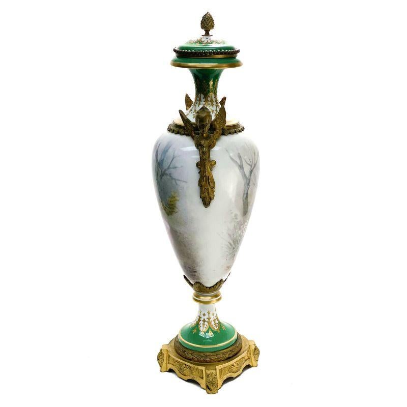 Sevres France porcelain hand painted decorative urn, late 19th century

A white and green ground and the central areas depict a hand painted scene of a beauty and cherub sitting in a forest. Artist signed towards the base. Gilt bronze handles in