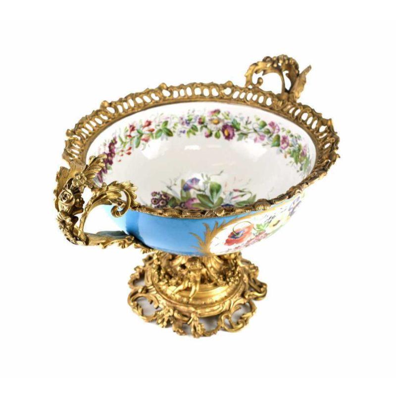 Sevres French Porcelain centerpiece bowl hand painted figural, Late 19th century.

A French, late 19th century, centerpiece with a hand painted outdoor scene of figural group, the interior decorated with floral sprigs. Mounted to gilt bronze with