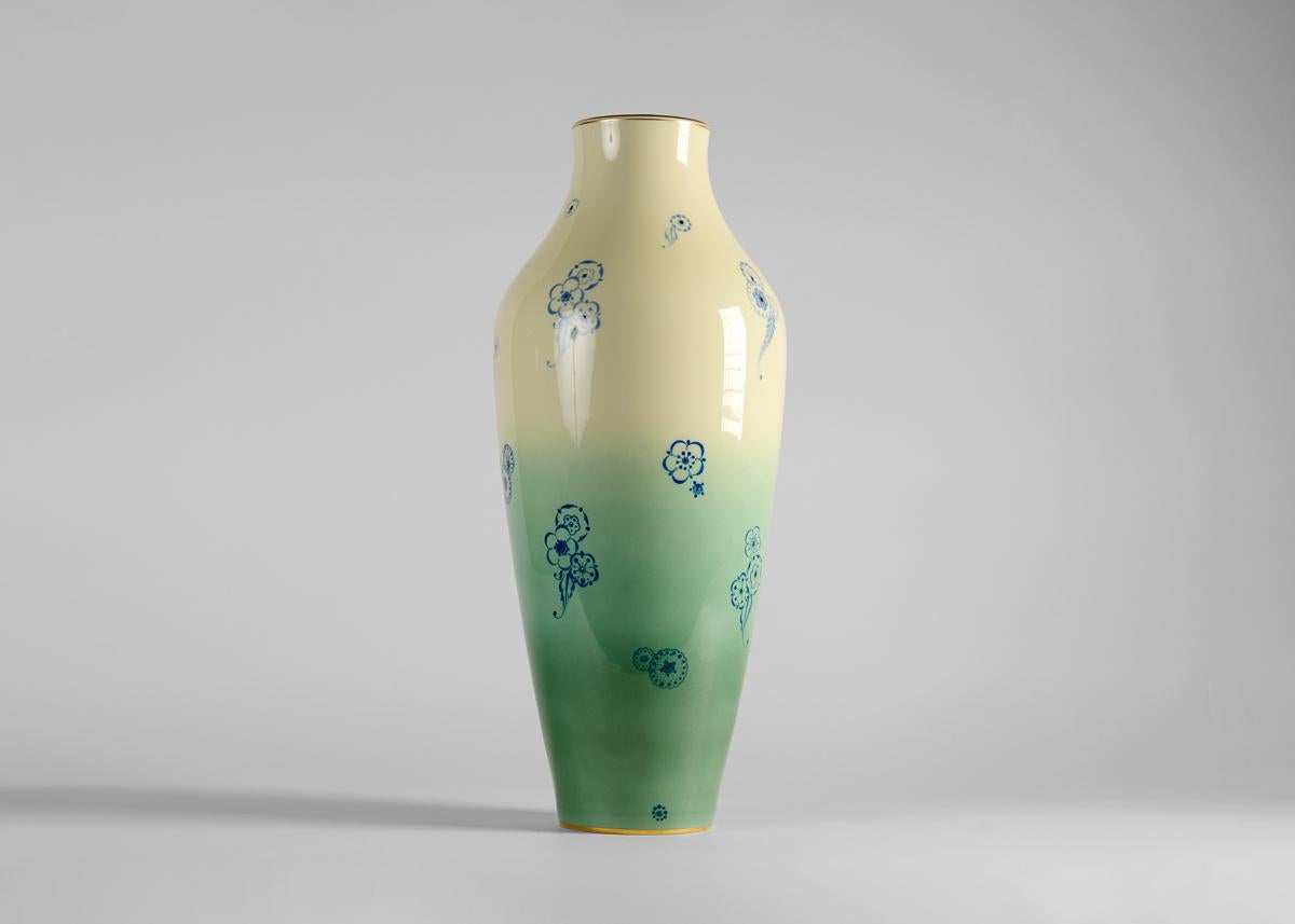 Grand et majestueux, ce vase Art déco est émaillé d'un dégradé croissant de jade, de turquoise et de crème, avec de petites fleurs stylisées, rappelant les estampes japonaises, dispersées sur la surface.
 
Marqué à l'intérieur du bord : MADE IN