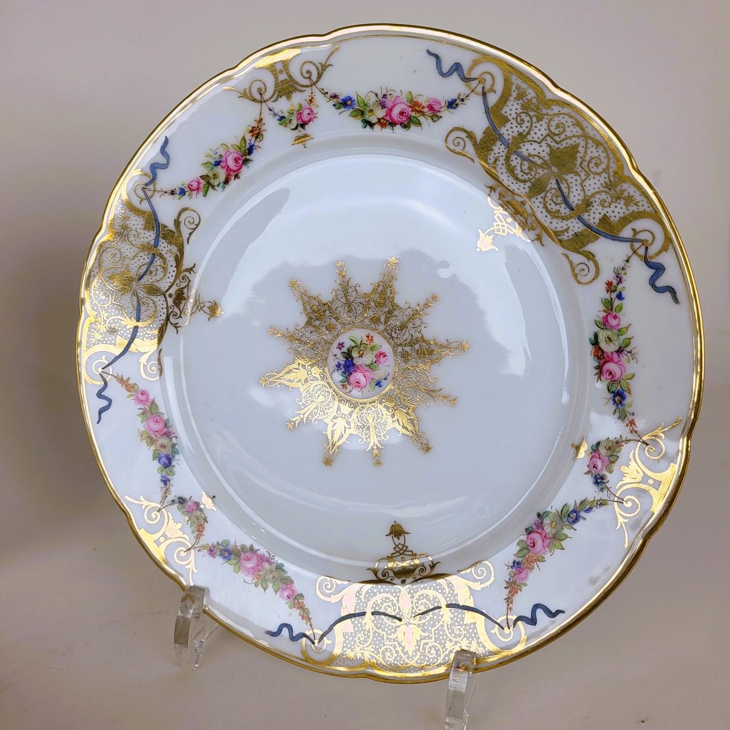 Set of 12 elegant white porcelain plates with a decoration of flowers, ribbons and colored rosettes, with gold highlights

Two are marked 