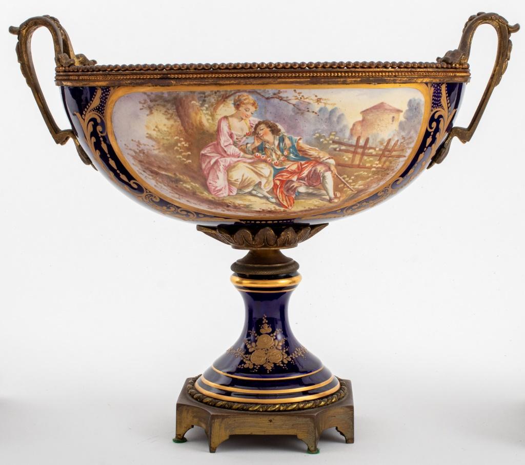 Sevres Marked Cobalt Blue Glazed Porcelain Garniture Set, comprising: one two-handled centerpiece bowl with hand-painted courting scenes of lovers and landscapes, and two vases with satyr mask form handles and vignettes depicting the classical
