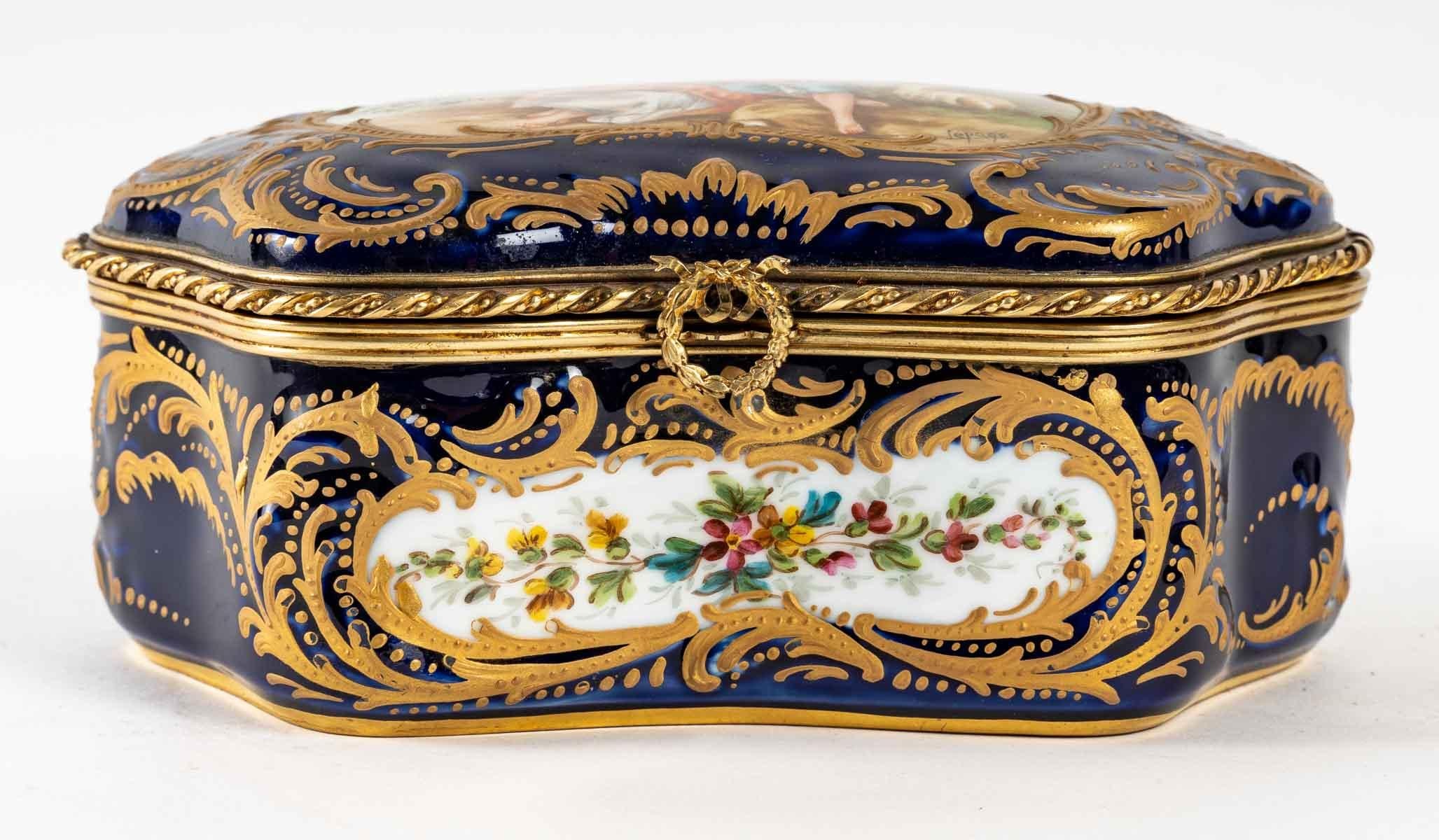 A Sèvres style royal blue porcelain box with a romantic scene of two lovers, early 20th century, Napoleon III style.
Measures: H: 8.5 cm, W: 20 cm, D: 14 cm.