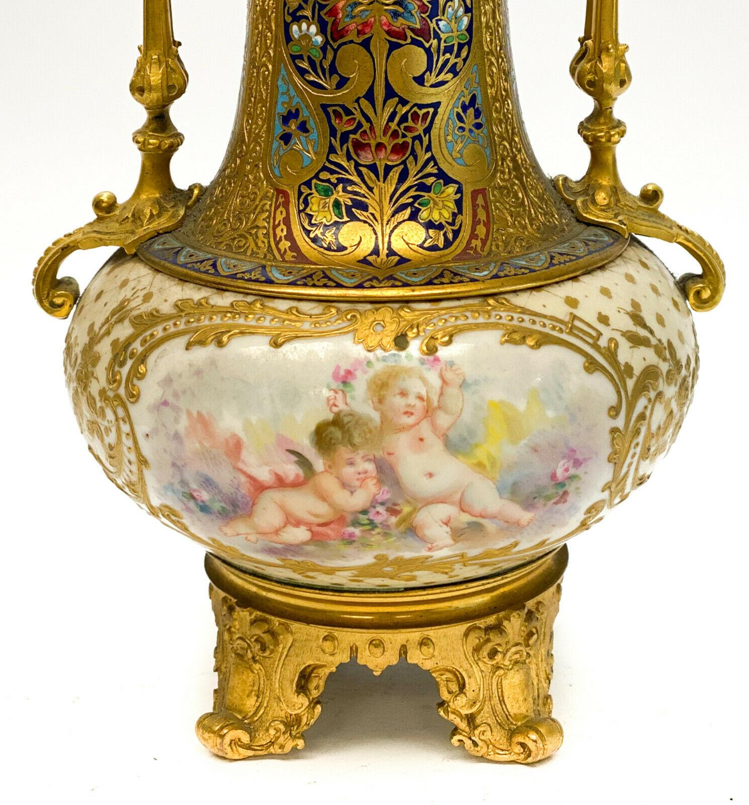 Sevres porcelain champleve enamel gilt bronze mounted twin handled vase, circa 1900. Hand painted floral bouquets to the central areas of the porcelain with gilt foliate scrolls. multicolored floral champleve enamel decoration to the gilt bronze. We