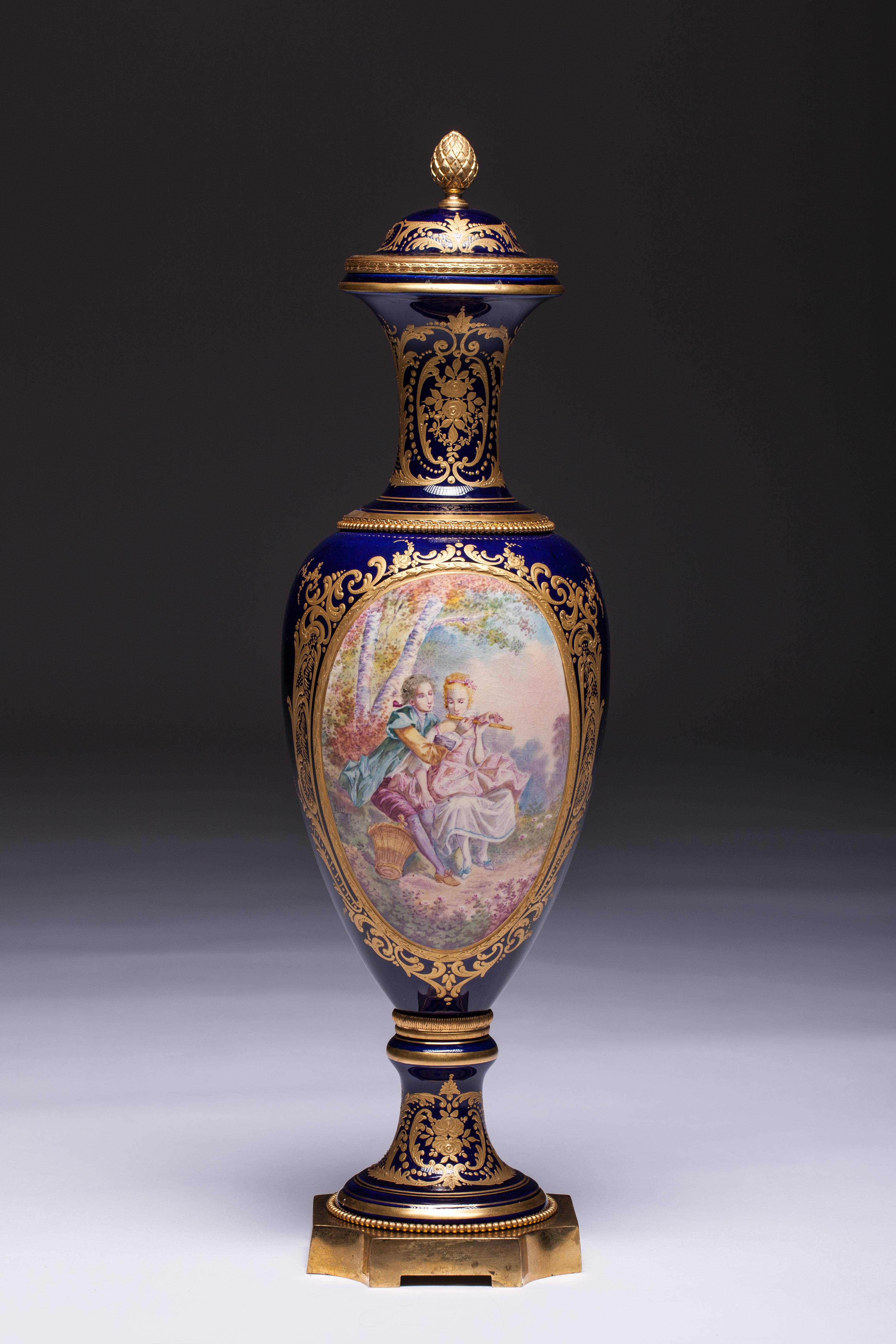 NB! Scratches here and there consistent with age and use

A good quality pair of 19th century 'Sevres' porcelain hand-painted classical vase, depicting romantic scenes to the panels, set in a dark blue background with gilded decoration and raised