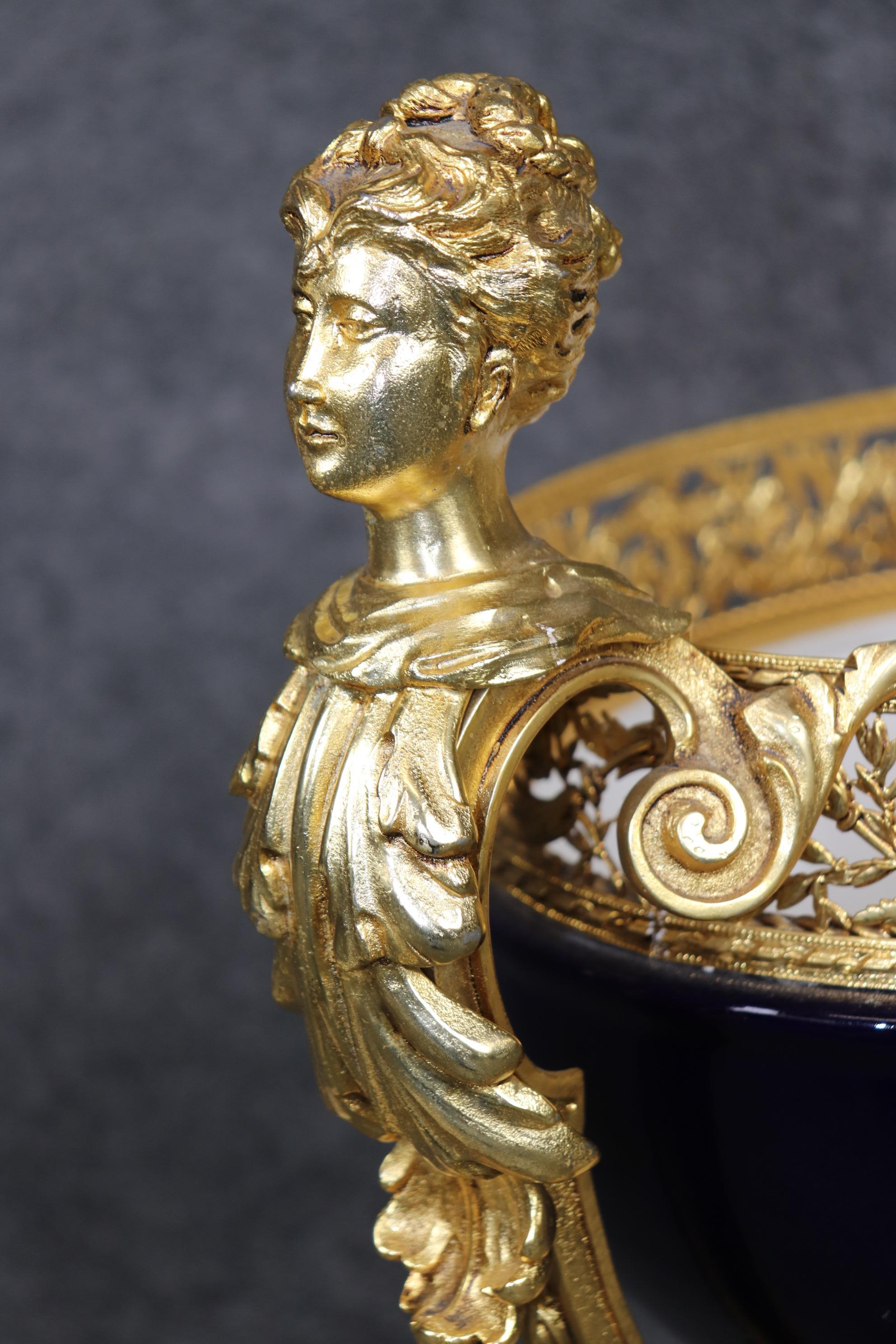 This is a stunning absolutely breathtaking royal blue and bright dore' bronze ceramic centerpiece with bronze reticulating ormolu and figural maiden heads. The piece is in good condition and because its quite large we recommend professional