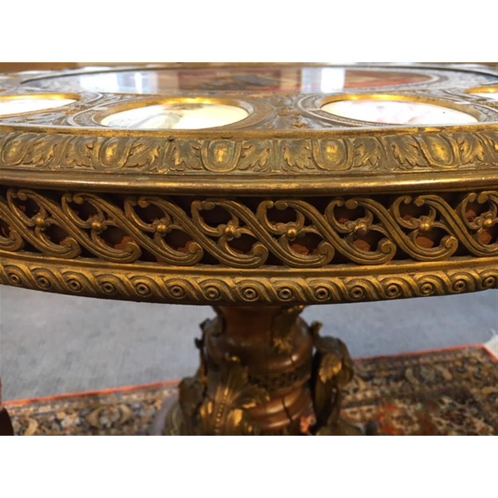 Important Sèvres style gilt bronze with porcelain plaques center table.
Round top with a scene of Louis XVI, surrounded by oval plaques depicting figures including Marie Antoinette, Louis XVII, and Mme. Elisabeth, on a mount-decorated turned