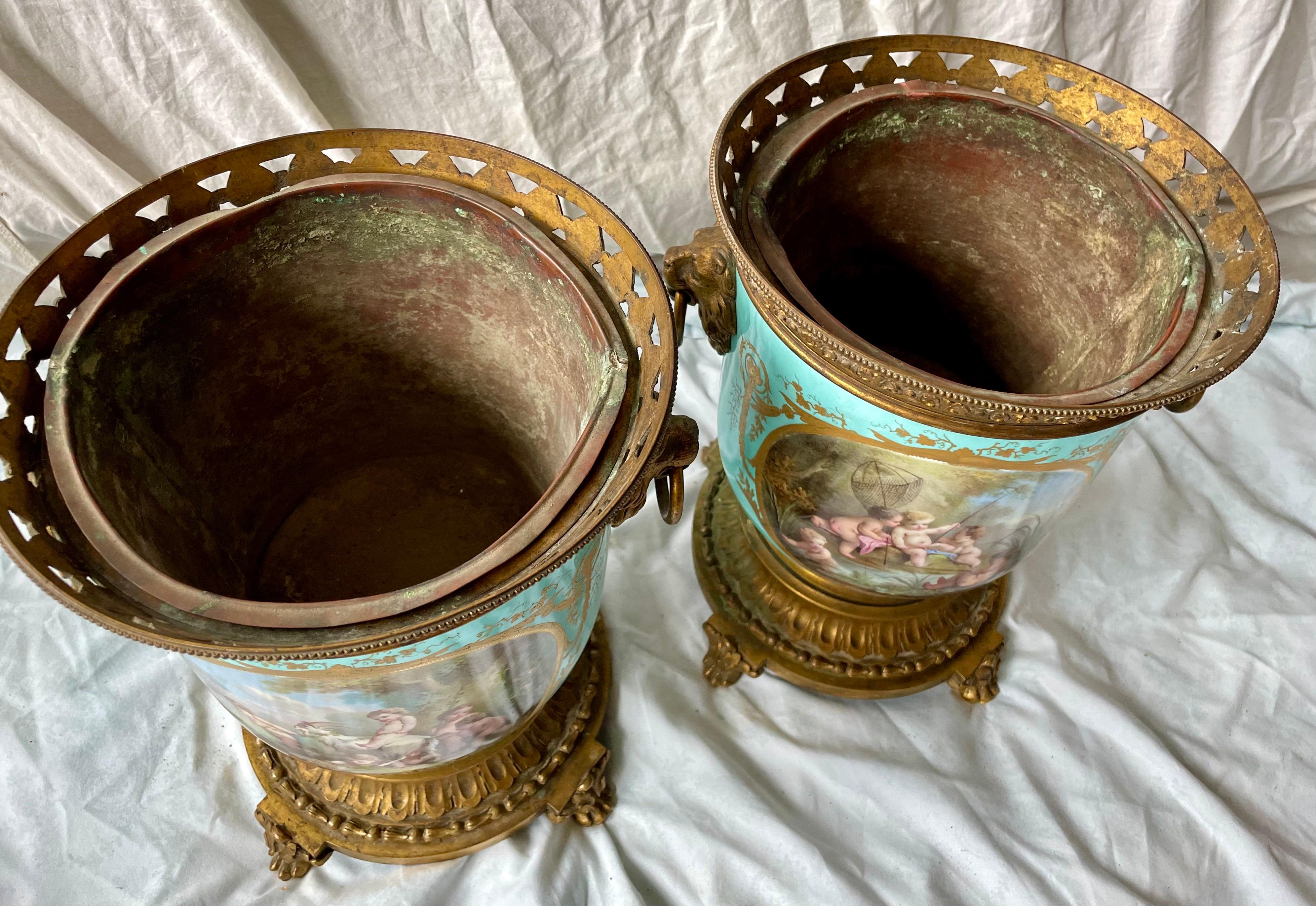 Ecco una coppia di vasi per cache dipinti a mano con fantastiche raffigurazioni di putti che cavalcano su un lato del vaso e un collage artistico di pezzi decorativi sull'altro. Lo sfondo blu uovo è una fantastica valorizzazione per le quattro