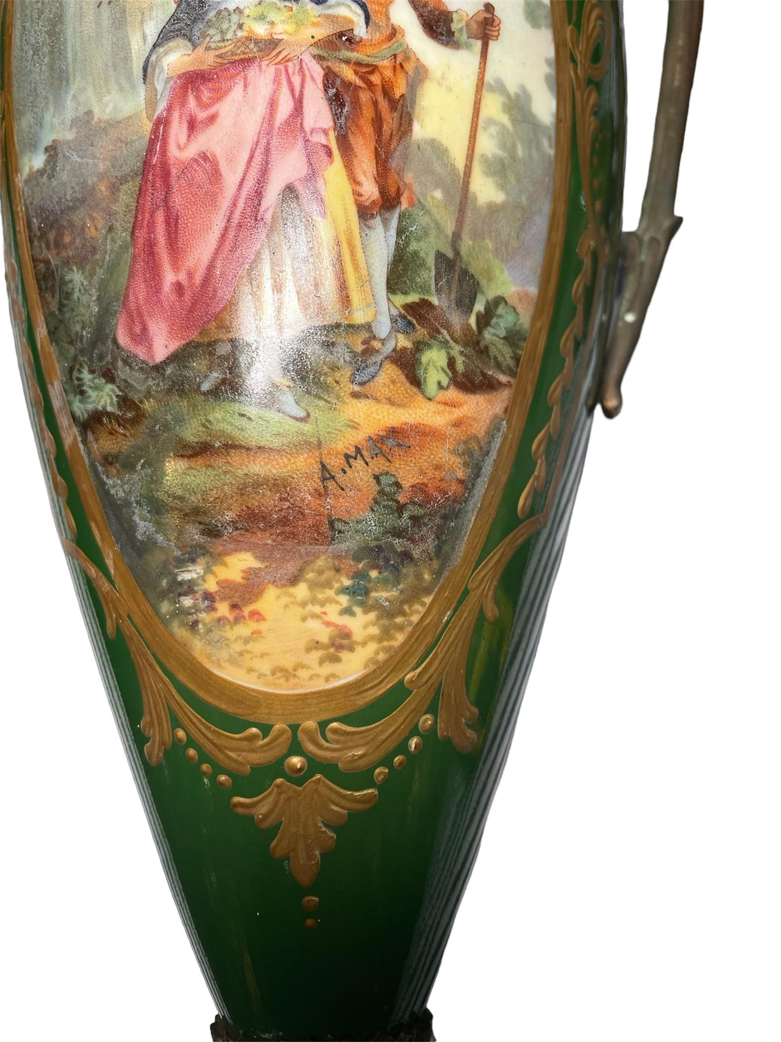 These are a pair of Sevres Style ormolu and green hand-painted and signed lidded porcelain urn vases. Each one depicting a scene of young couples peasants. One is depicting a young girl with a basket of flowers and hugged by a young boy holding a
