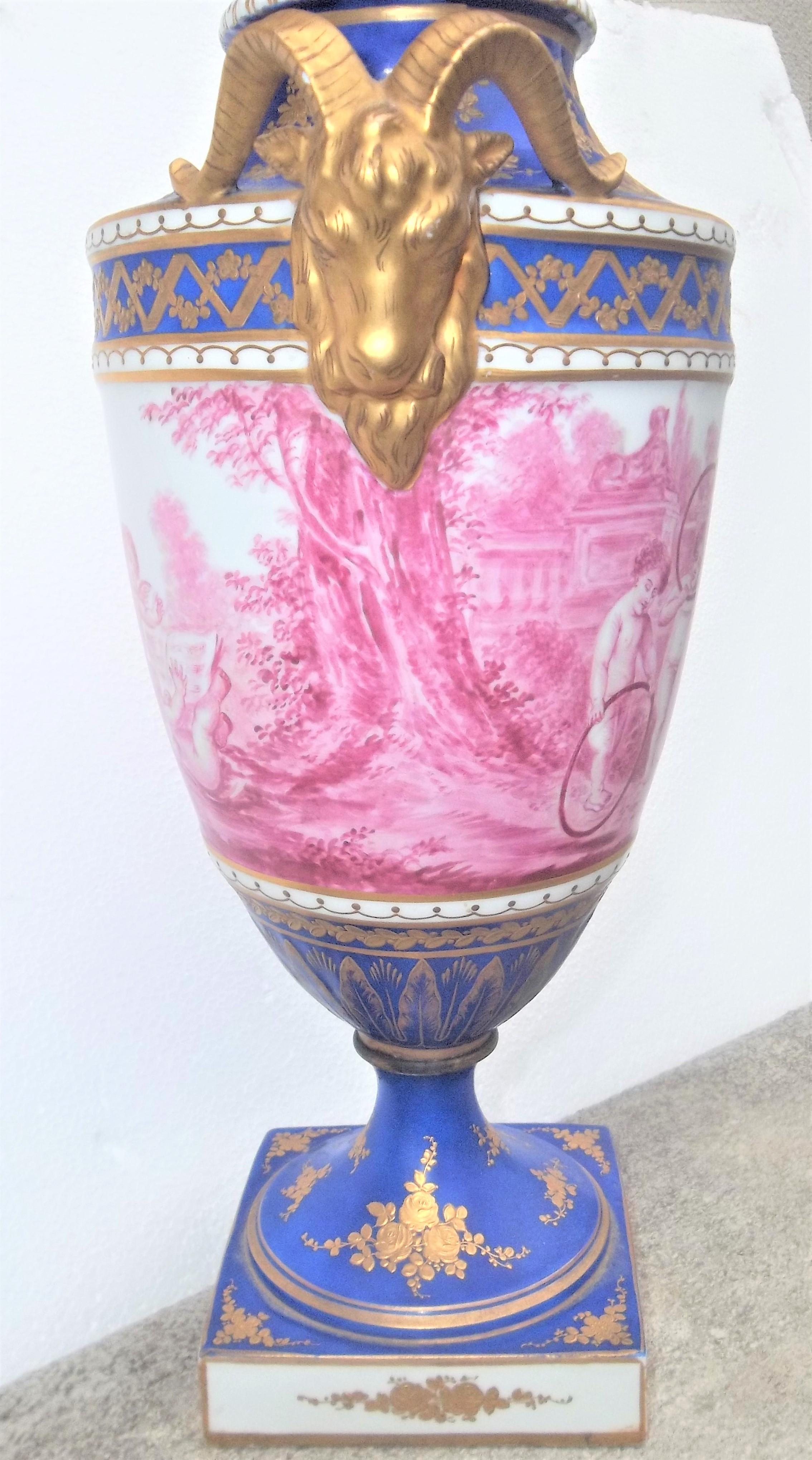 Sèvres-style parcel-gilt putti or cherub decorated covered urn having an urn-form body decorated in puce with a continuous scene of putti at play, signed Henri . The blue ground decorated with musical trophy and floral sprays .The sides flanked by