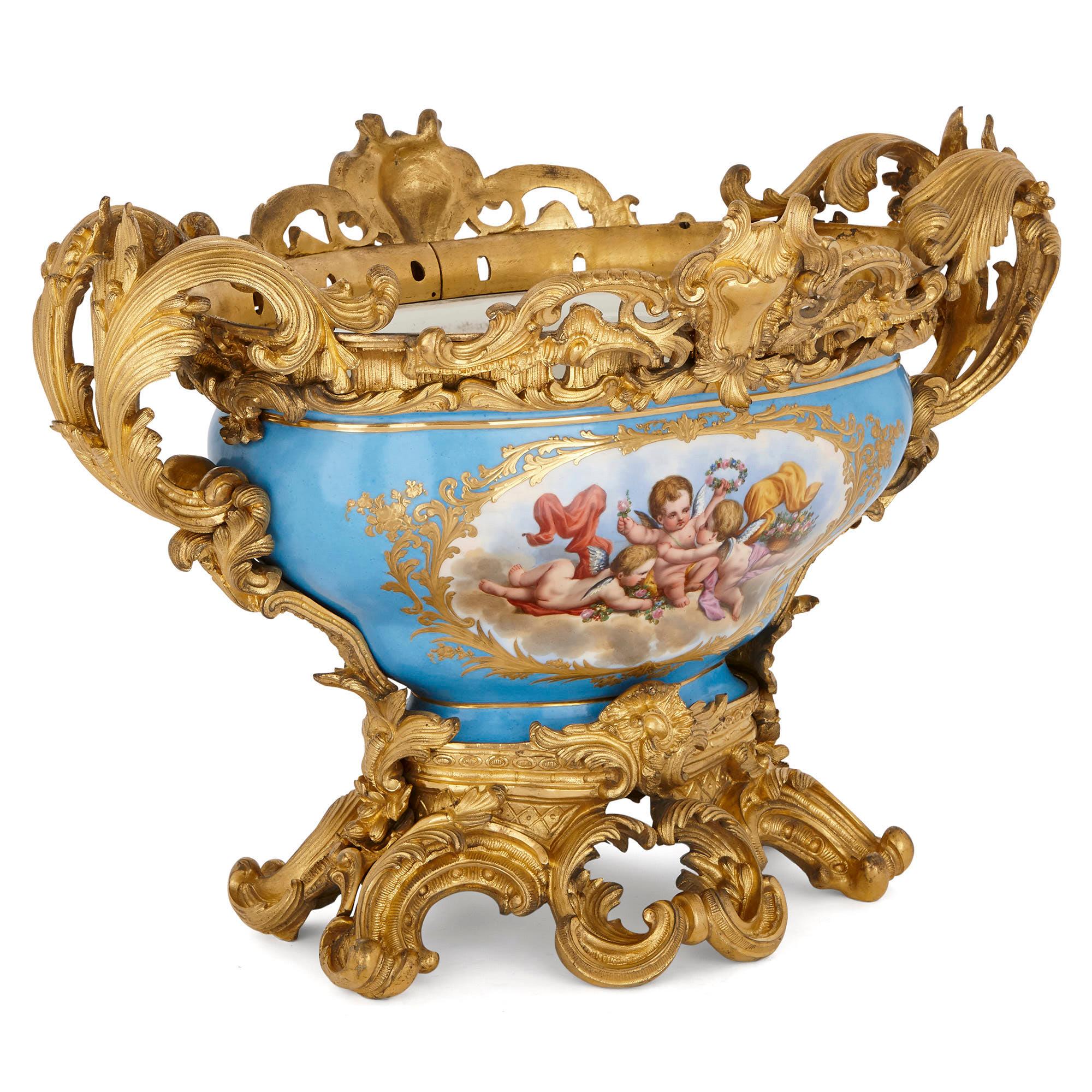 Cette exquise coupe centrale a été créée à la fin du XIXe siècle dans un style rococo du XVIIIe siècle, popularisé par la manufacture de porcelaine de Sèvres.

Le centre de table est composé d'un bol en porcelaine, avec un corps large posé sur un