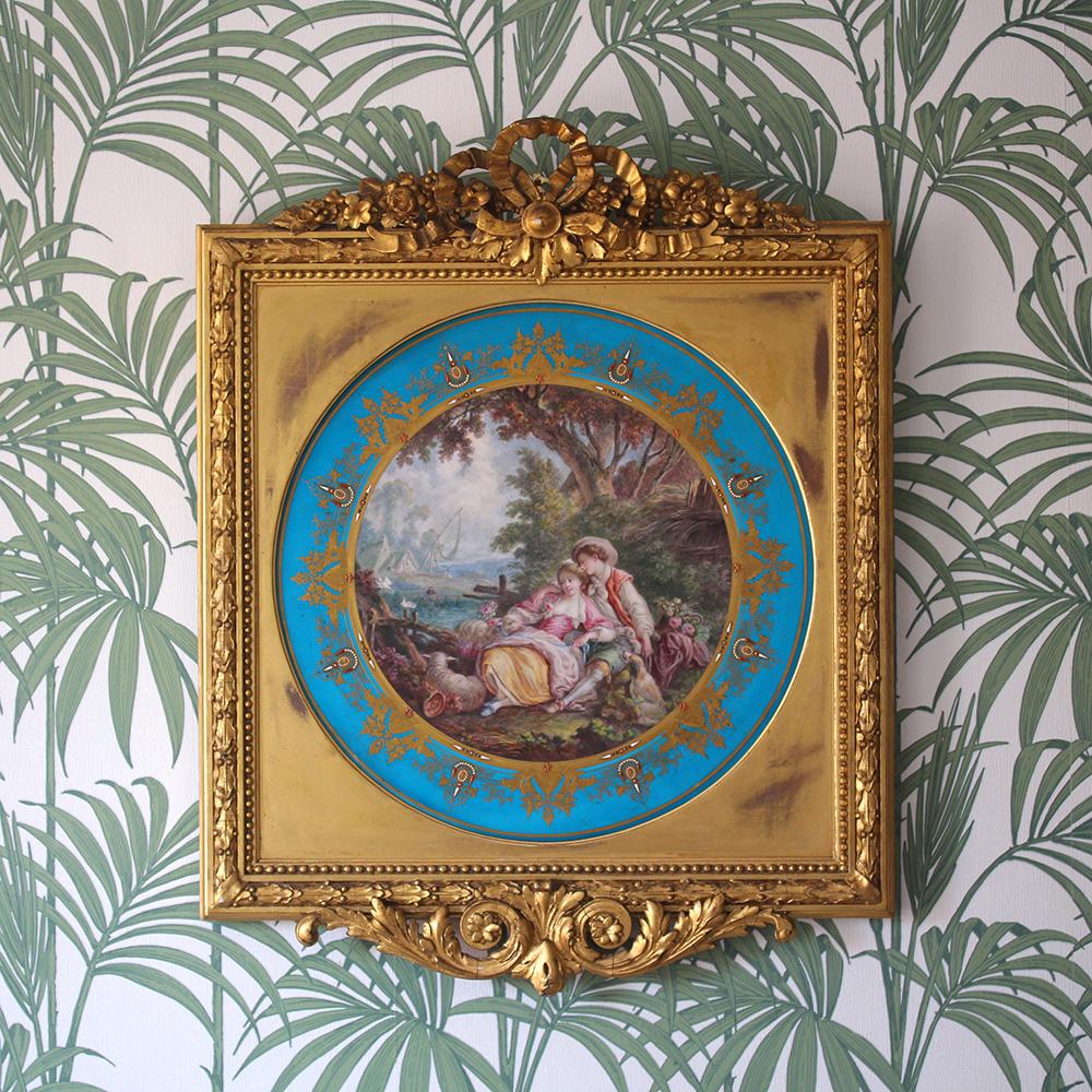 'Sevres' late 19th century porcelain circular plaque. The plaque of large form extensively decorated with a central romantic scene with a couple laying amongst foliage and flowers alongside a small lake with a sheep and dog beside them. To the