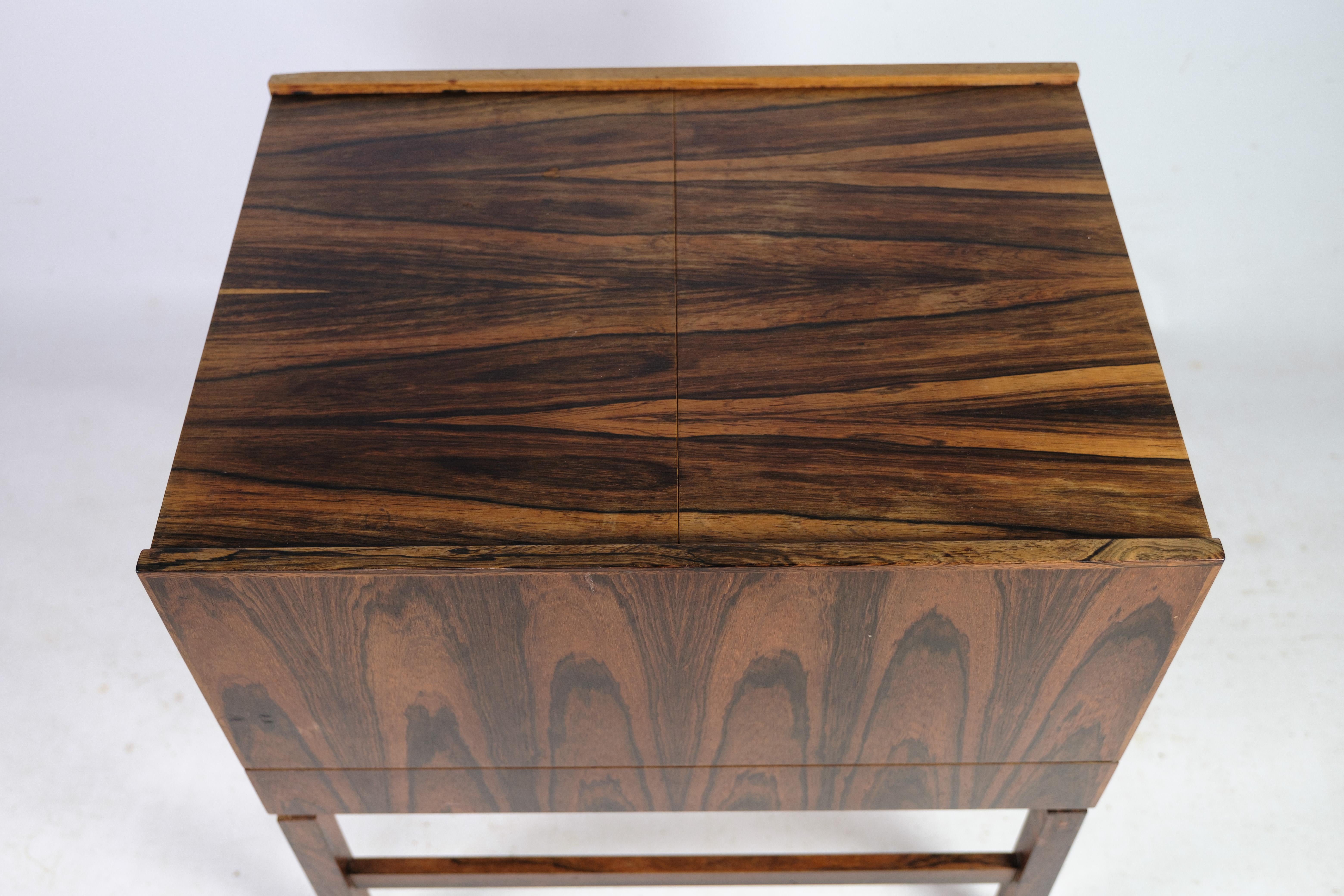 
This vintage sewing table/bar table, supported by rosewood legs, exemplifies the exquisite Danish furniture design of the 1960s. Manufactured in Denmark, it boasts exceptional quality and a captivating design.

Featuring a slotted opening in the