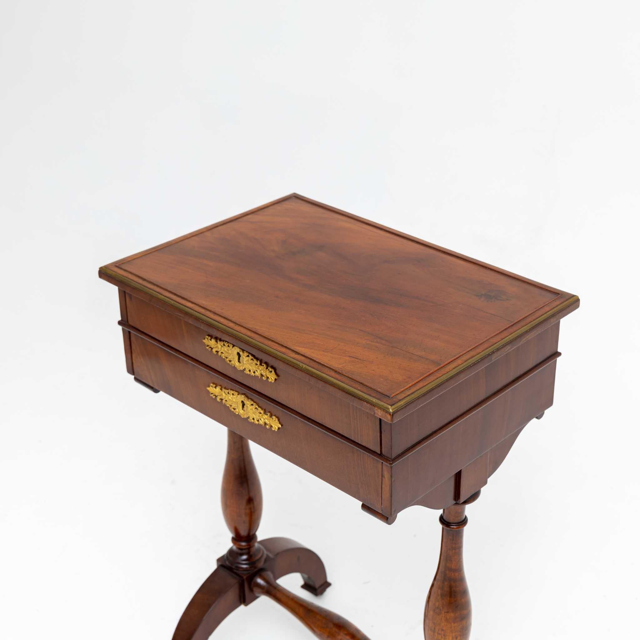 Empire sewing table made of mahogany with two drawers and baluster legs. The sewing table stands on small casters and has an inventory label on the bottom: Jegenstorf Castle No. 00976.