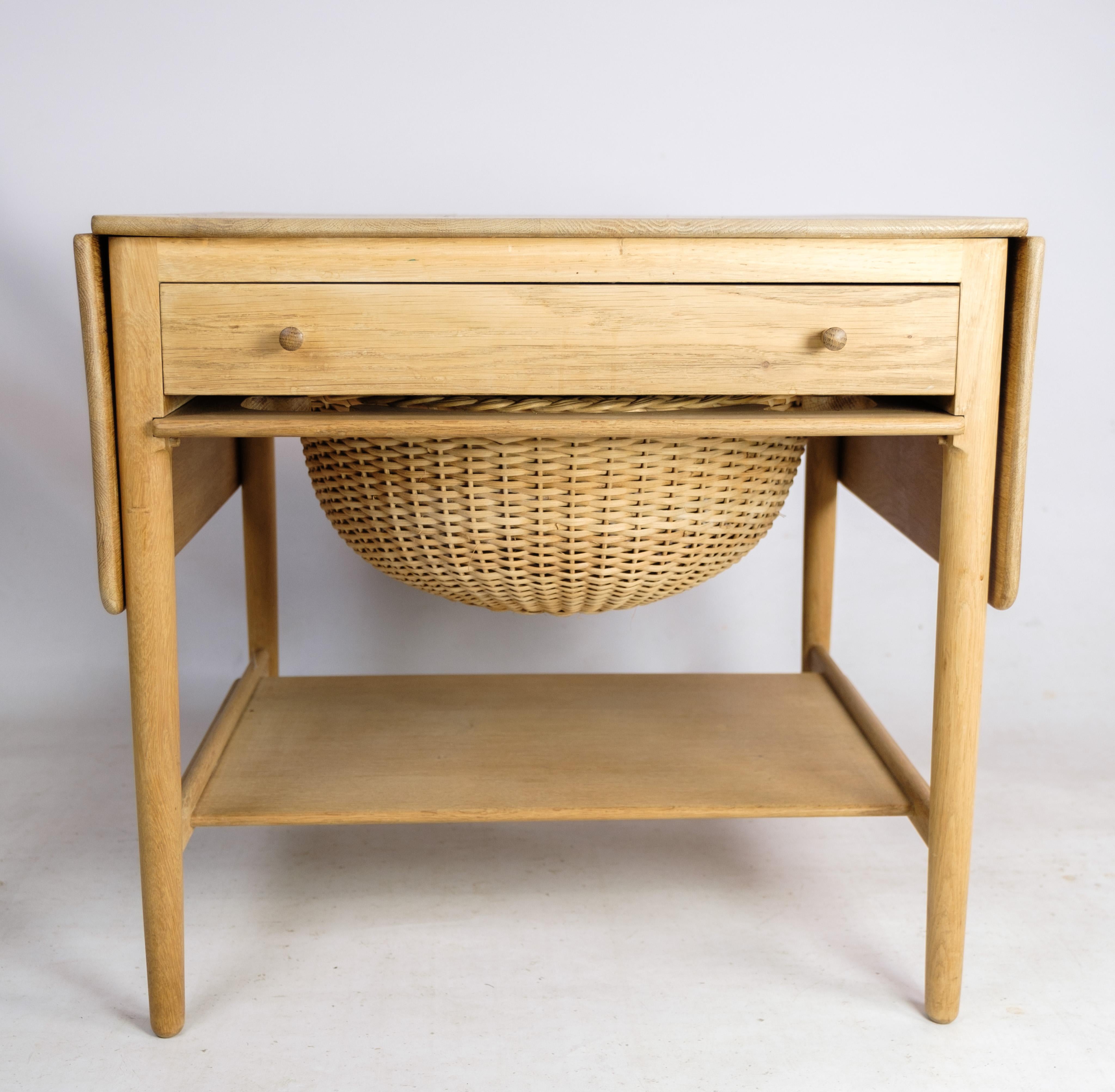 Sewing table in oak, designed by Hans J. Wegner with wicker basket, drawer and two folding plates from around the 1960s.

This product will be inspected thoroughly at our professional workshop by our educated employees, who assure the product