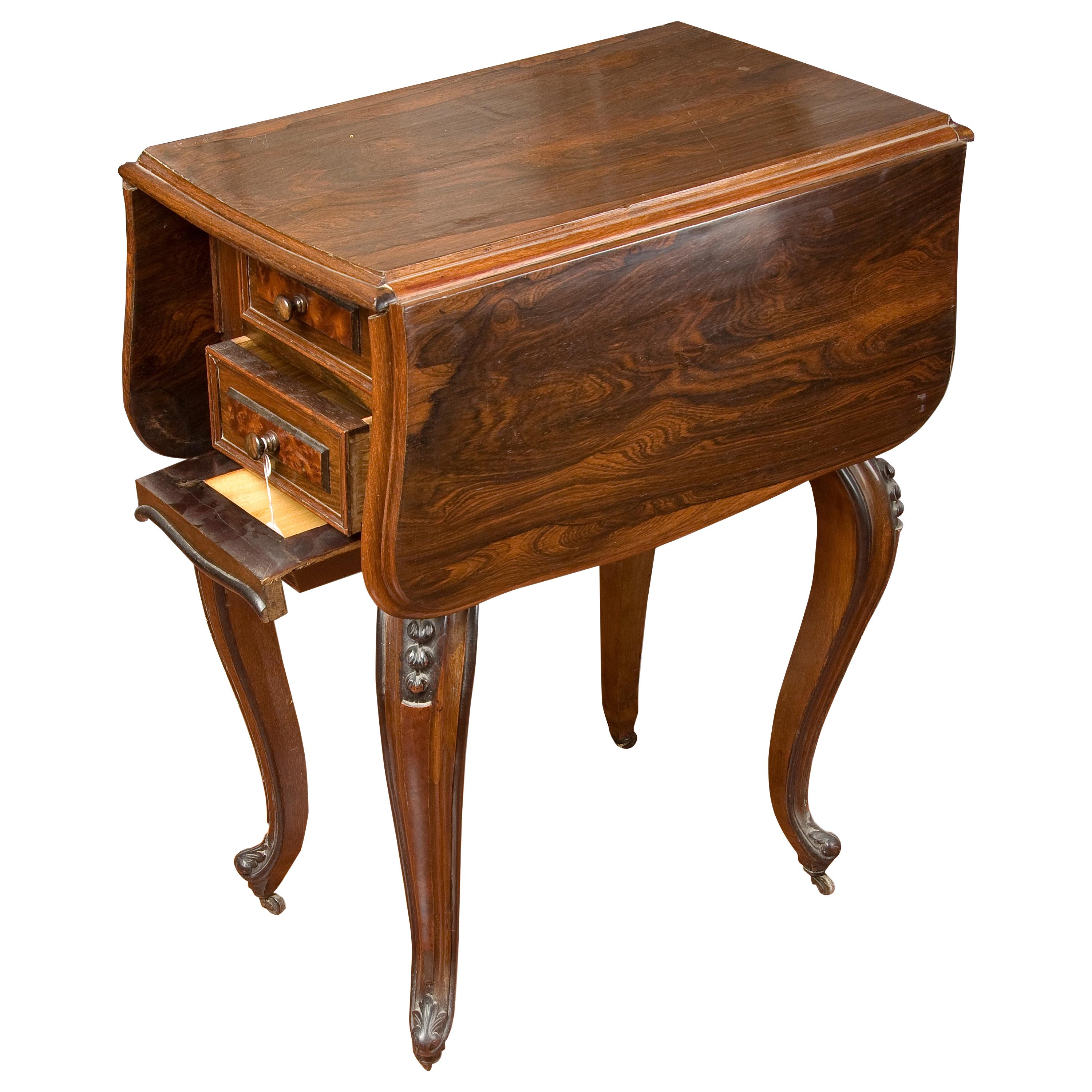 Rosewood sewing table with wings, 19th century.
Narrow coffee table with two folding wings supported on four cabriolet legs decorated with carved vegetable garlands and metal casters. The front features two drawers and a removable table. The purity