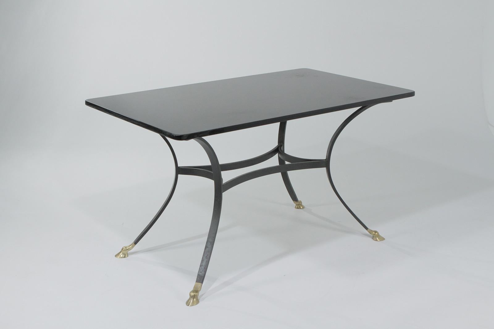 A glamorous medium sized dining table having a sexy thick black glass top and black wrought iron base with cast bronze hoof feet in the manner of labarge. The top is original with minor signs of surface use.

