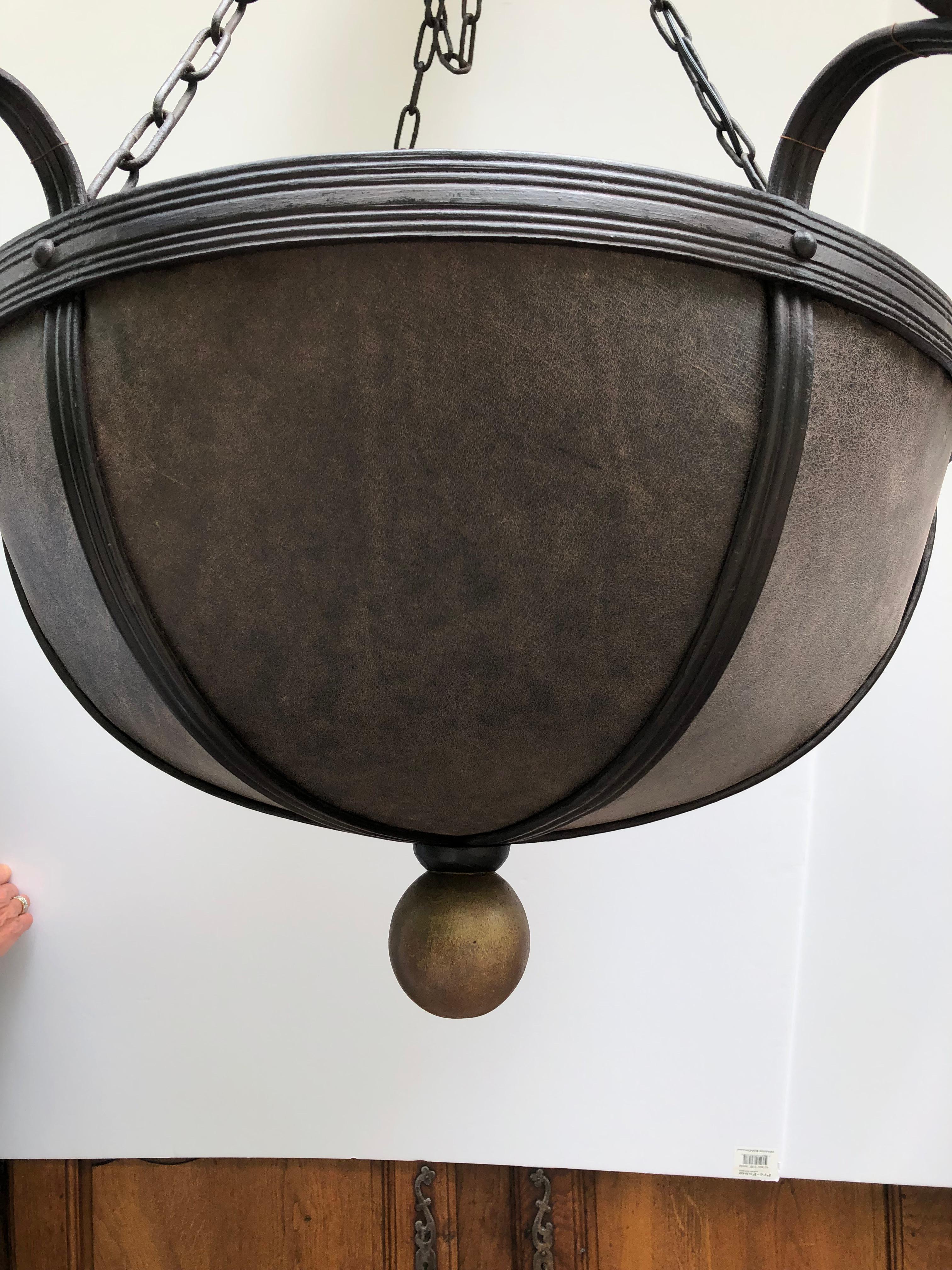 Large impressive bowl shaped chandelier made of yummy brown leather and dark brown hand forged iron. There are 6 lights around the periphery and a matte gold finial ball at the bottom.