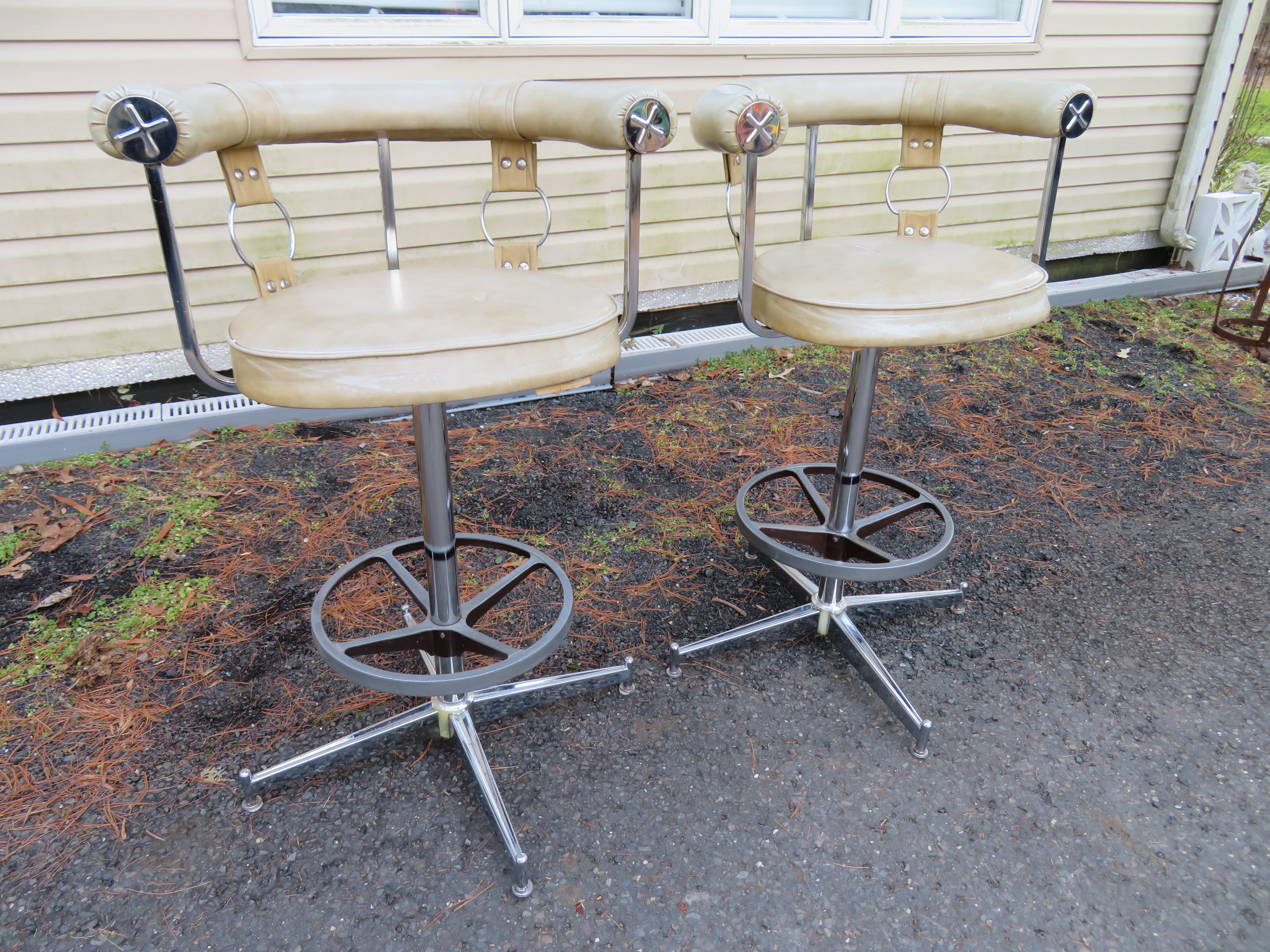 A set of 2 Gucci style chrome bar stools with faux leather seats and fun giant rings with straps. These will need to be reupholstered but we just love the thick rolled backrest with large chromed embossed end caps-very stylish. We think these would