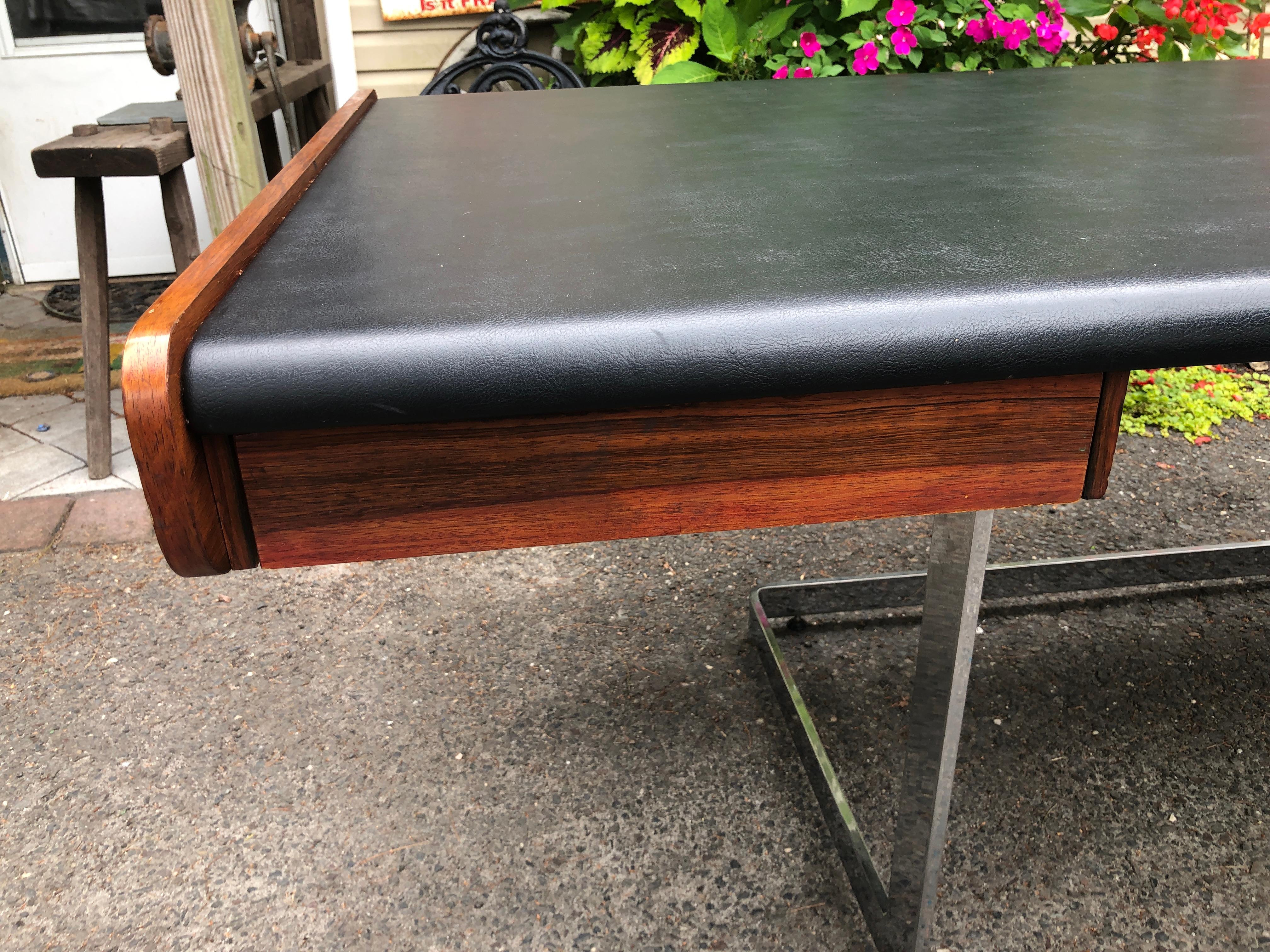 This sexy slim Ste-Marie and Laurent desk has beautiful rosewood grain and a black faux leather top. This Mid-Century desk floats on a modern chrome cantilever base and is finished on all sides. It measures 28.5