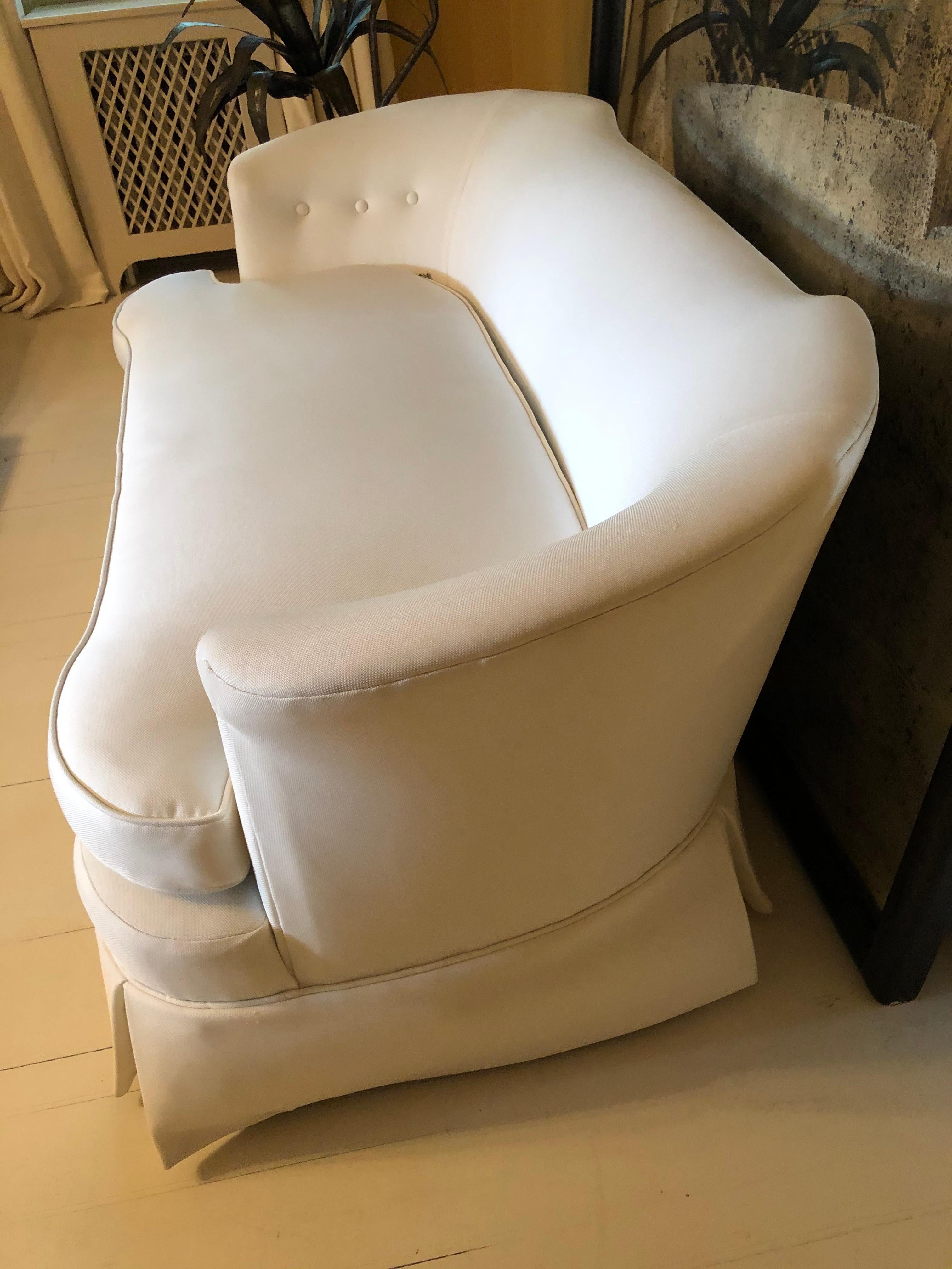 A sophisticated vintage settee that has been updated in a new crisp, white cotton blend upholstery. The settee has a lovely curved back and is decorated on each side with three covered buttons. A down blend cushion and a tailored pleated skirt