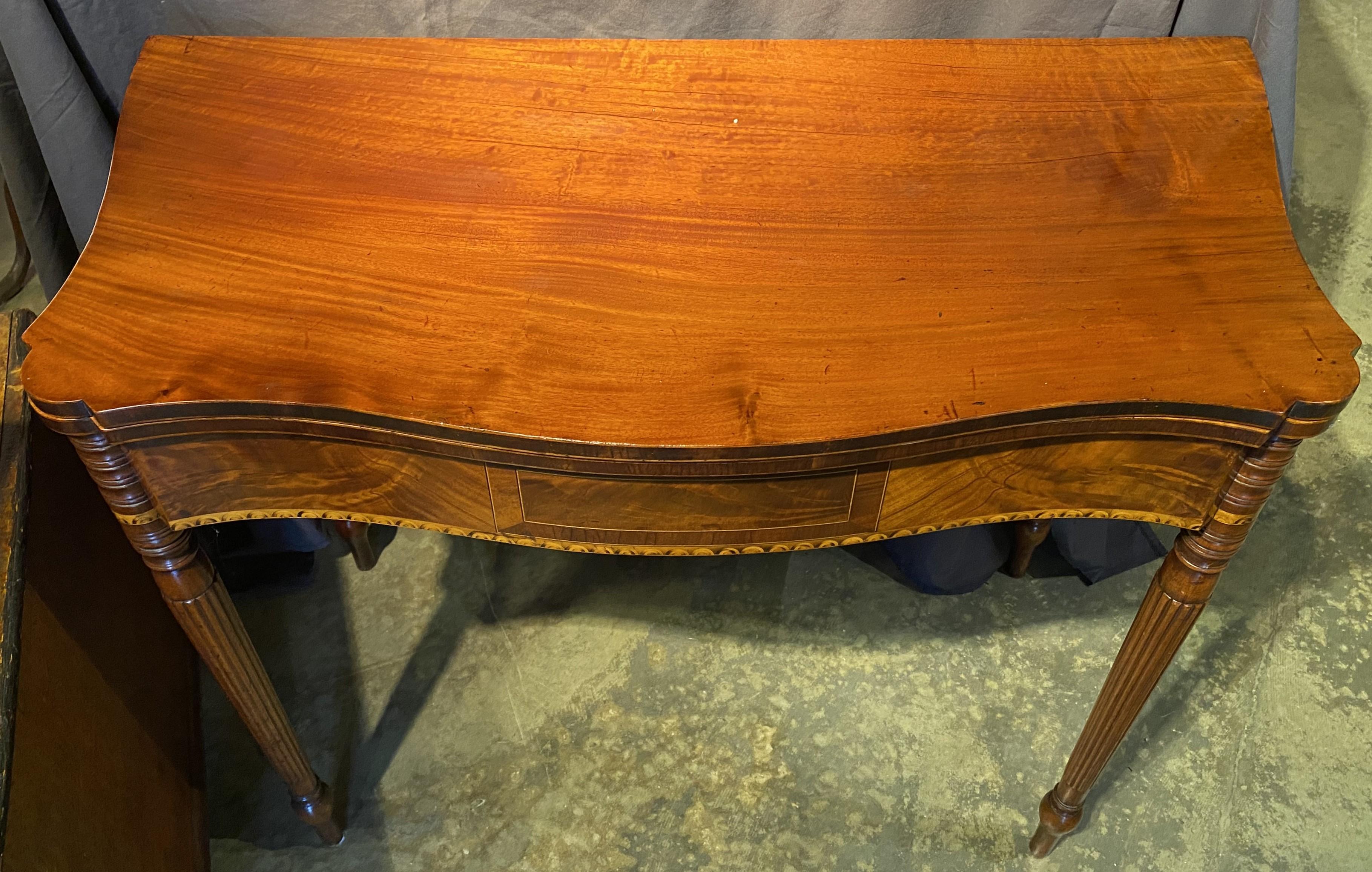 A beautifully detailed Seymour School Federal Period hand carved mahogany gaming table with shaped top, lunette frieze satinwood inlay, and striking flame mahogany top, with nicely turned and reeded legs. The table dates to circa 1810  in very good