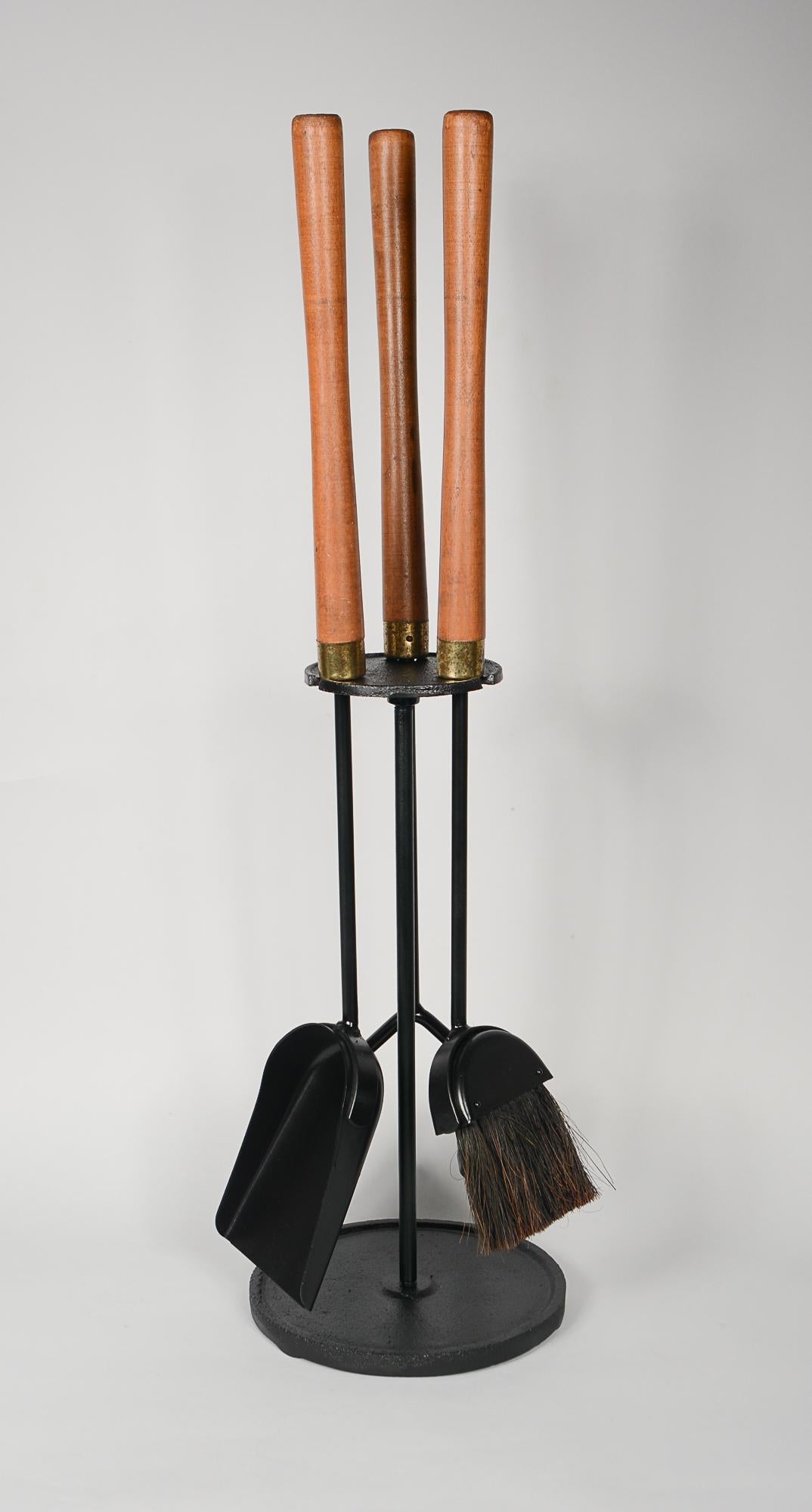 Set of walnut handle fireplace tools by Seymour Mfg. The set includes a poker, broom and shovel. These are well made sturdy tools. The iron appears to be recently painted. The handles have the original finish with minor wear. The brass plated