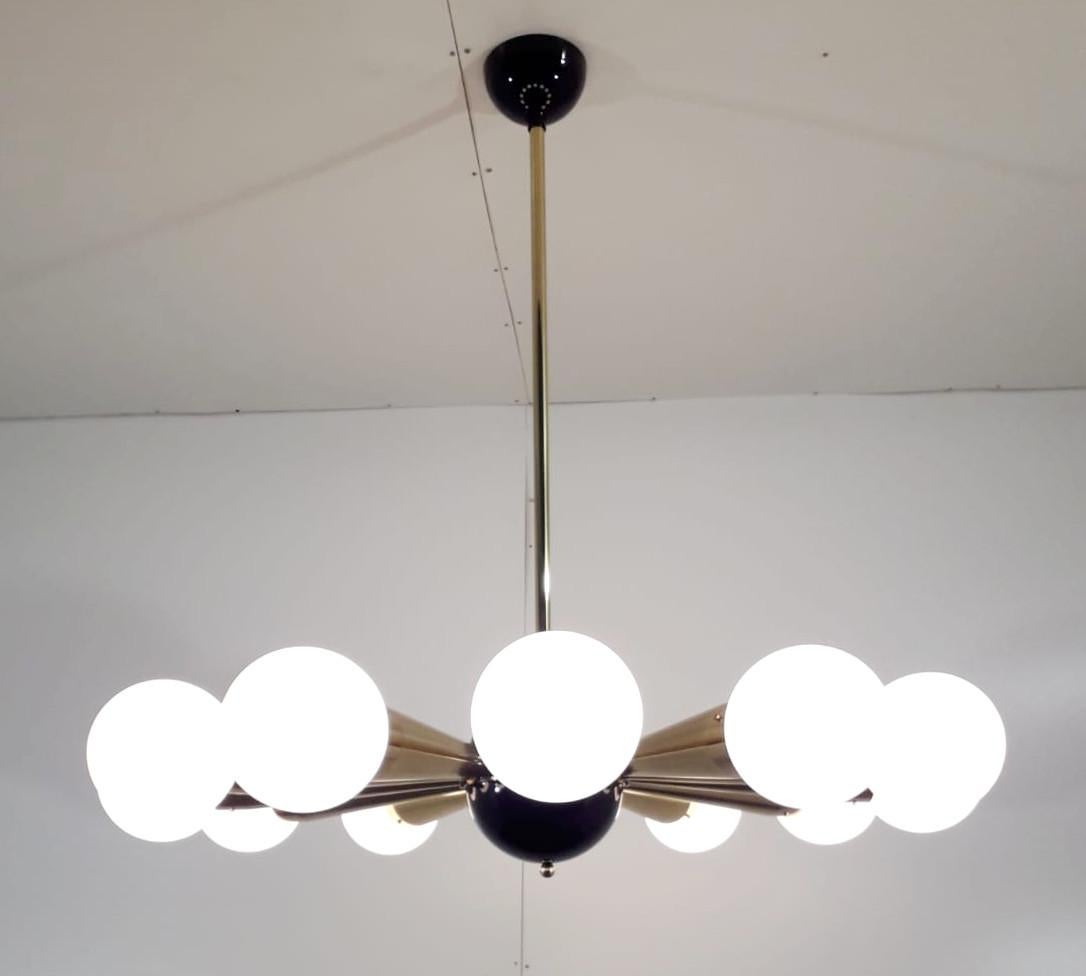 Italian chandelier with glossy white Murano glass globes mounted on polished brass frame with black enameled center and ceiling canopy, designed by Fabio Bergomi for Fabio Ltd, made in Italy
12 lights / E12 or E14 type / max 40W each
Measures:
