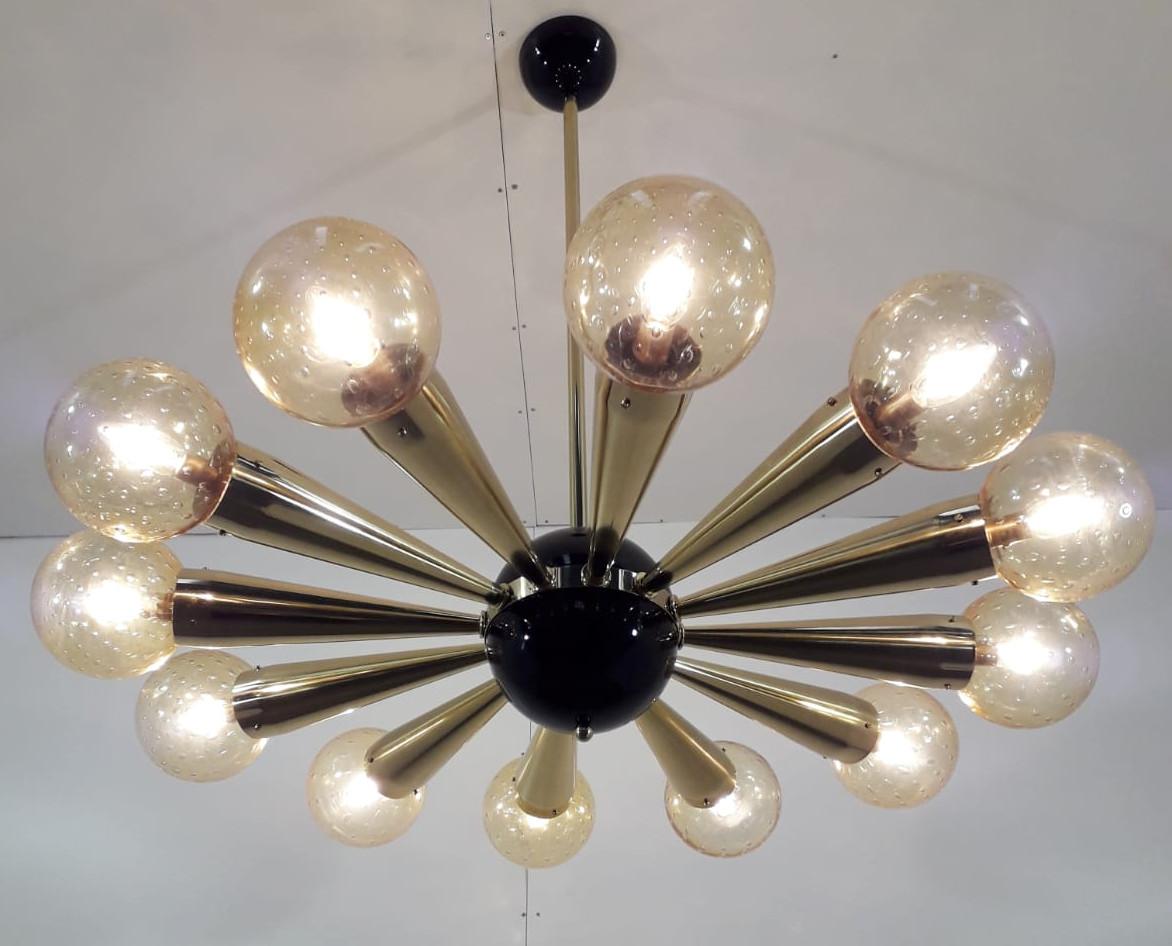 Italian chandelier with amber Murano glass globes with carefully blown bubbles within the glass using Bollicine technique, mounted on polished brass frame with black enameled center and ceiling canopy / Designed by Fabio Bergomi for Fabio Ltd / Made