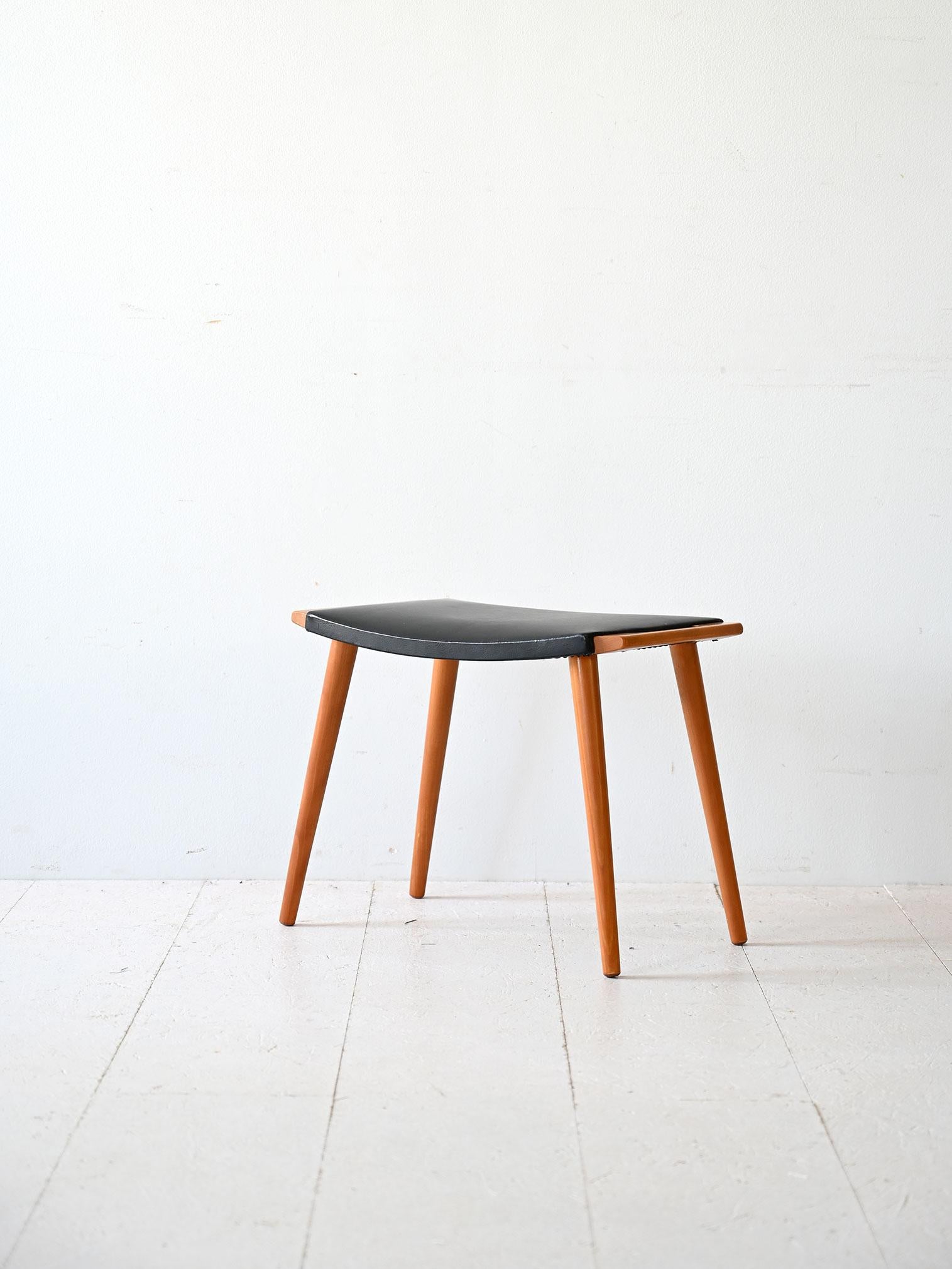 Sgabello vintage con struttura in legno di betulla e seduta in similpelle nera. 

Caratterizzato dalle gambe coniche e dalla presenza delle maniglie in legno. Pratico e leggere può essere utilizzato sia come poggiapiedi che come sgabellino