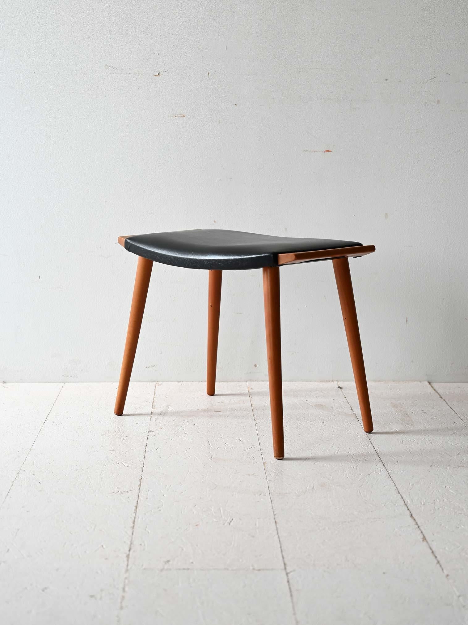 Vintage-Hocker mit Gestell aus Birkenholz und schwarzem Kunstledersitz. 

Kennzeichnend sind die konischen Beine und die Holzgriffe. Praktisch und leicht, kann er sowohl als Fußstütze als auch als zusätzlicher Hocker verwendet werden.
Guter Zustand.